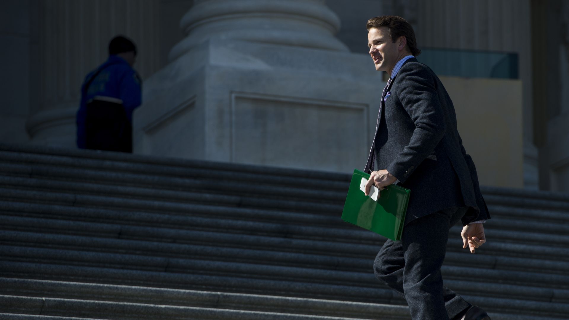 Former congressman Aaron Schock walks up the Capitol steps holding a green folder. 