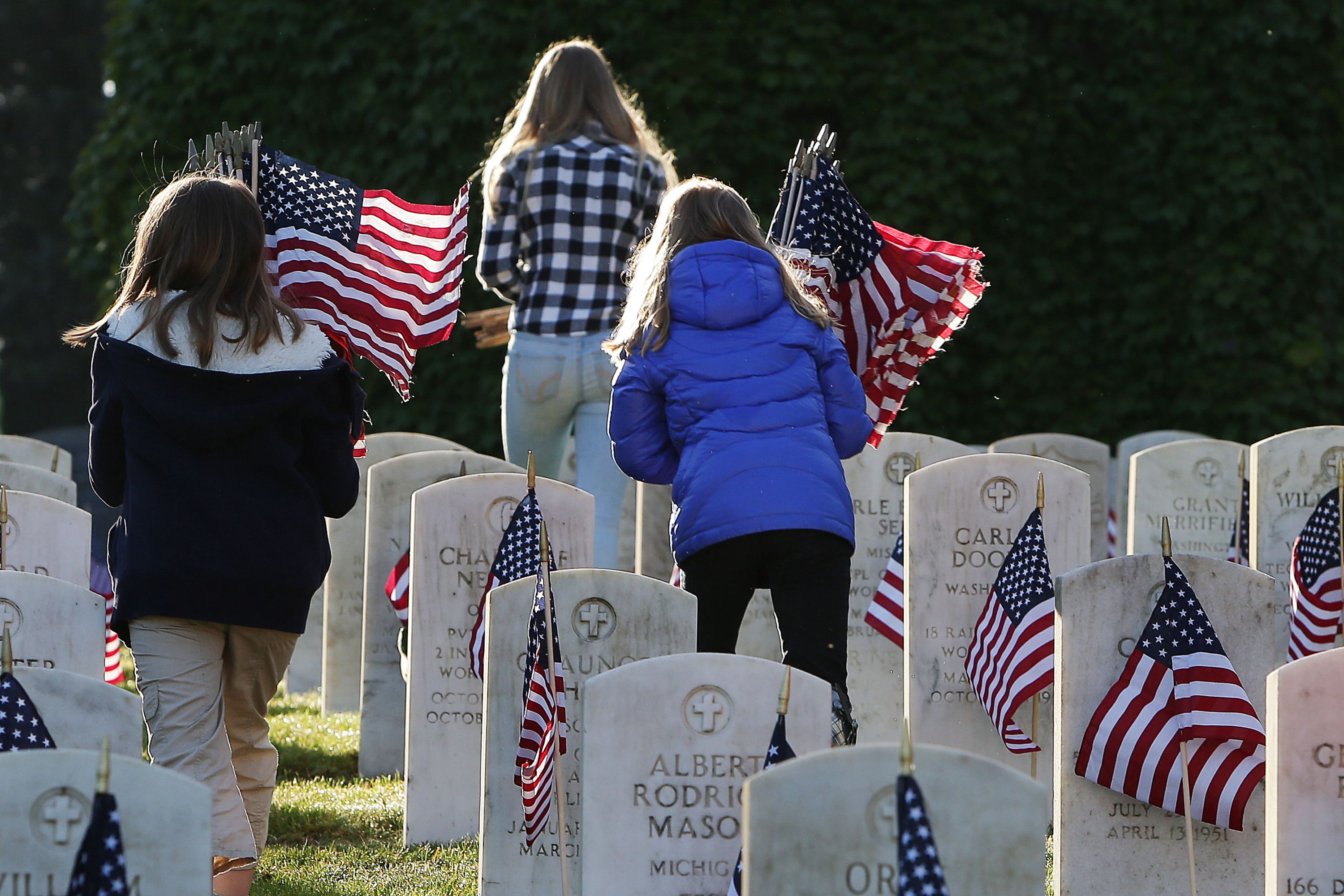 Children place flags on headstones before a Memorial Day ceremony.