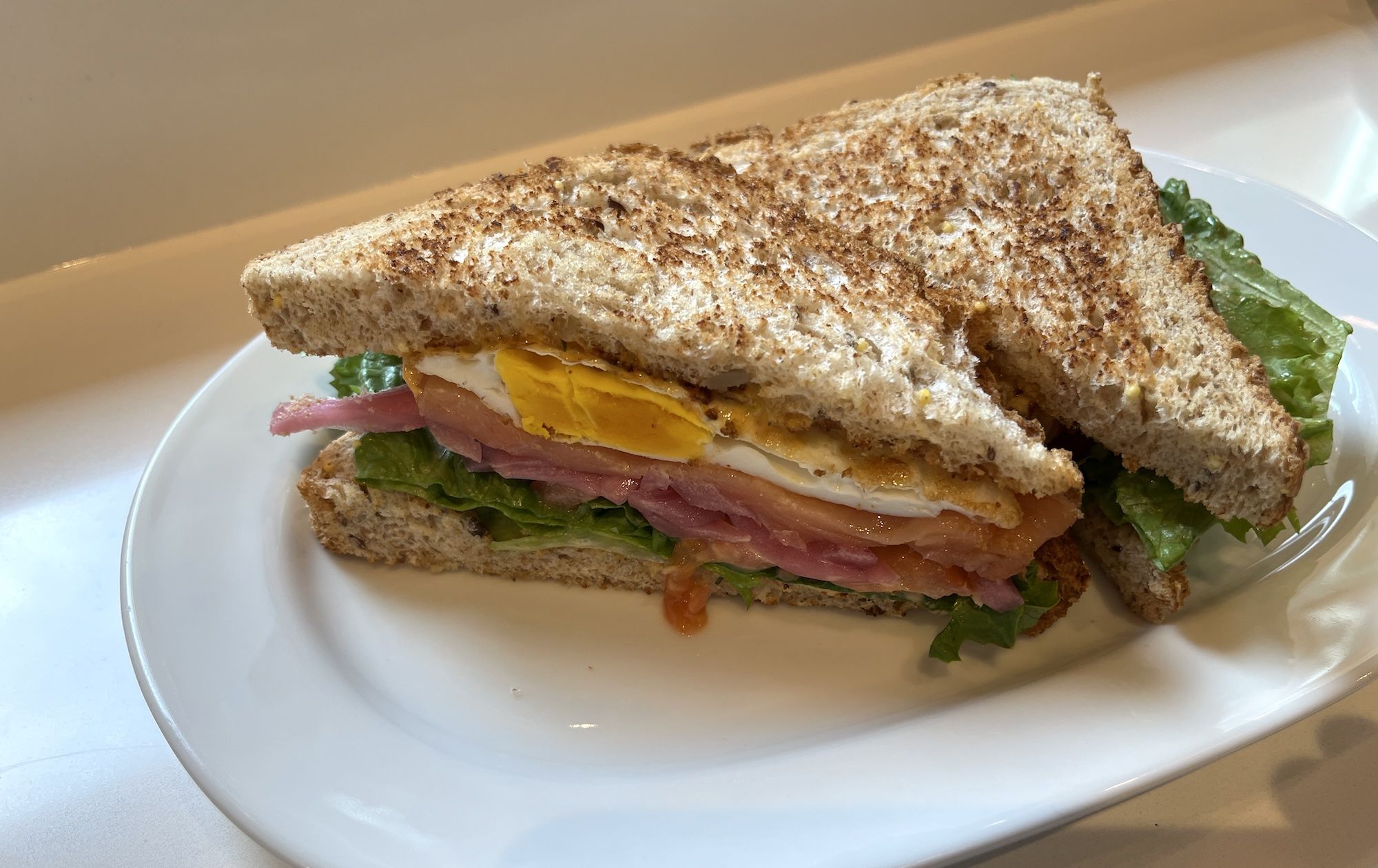 Club sandwich with a fried egg, salmon, lettuce.