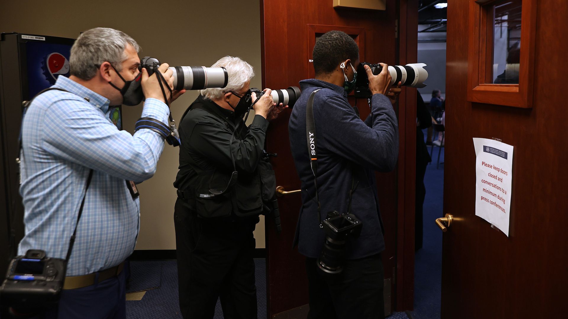 Photographers are seen taking pictures through a door during a news conference at the Capitol about D.C. statehood.