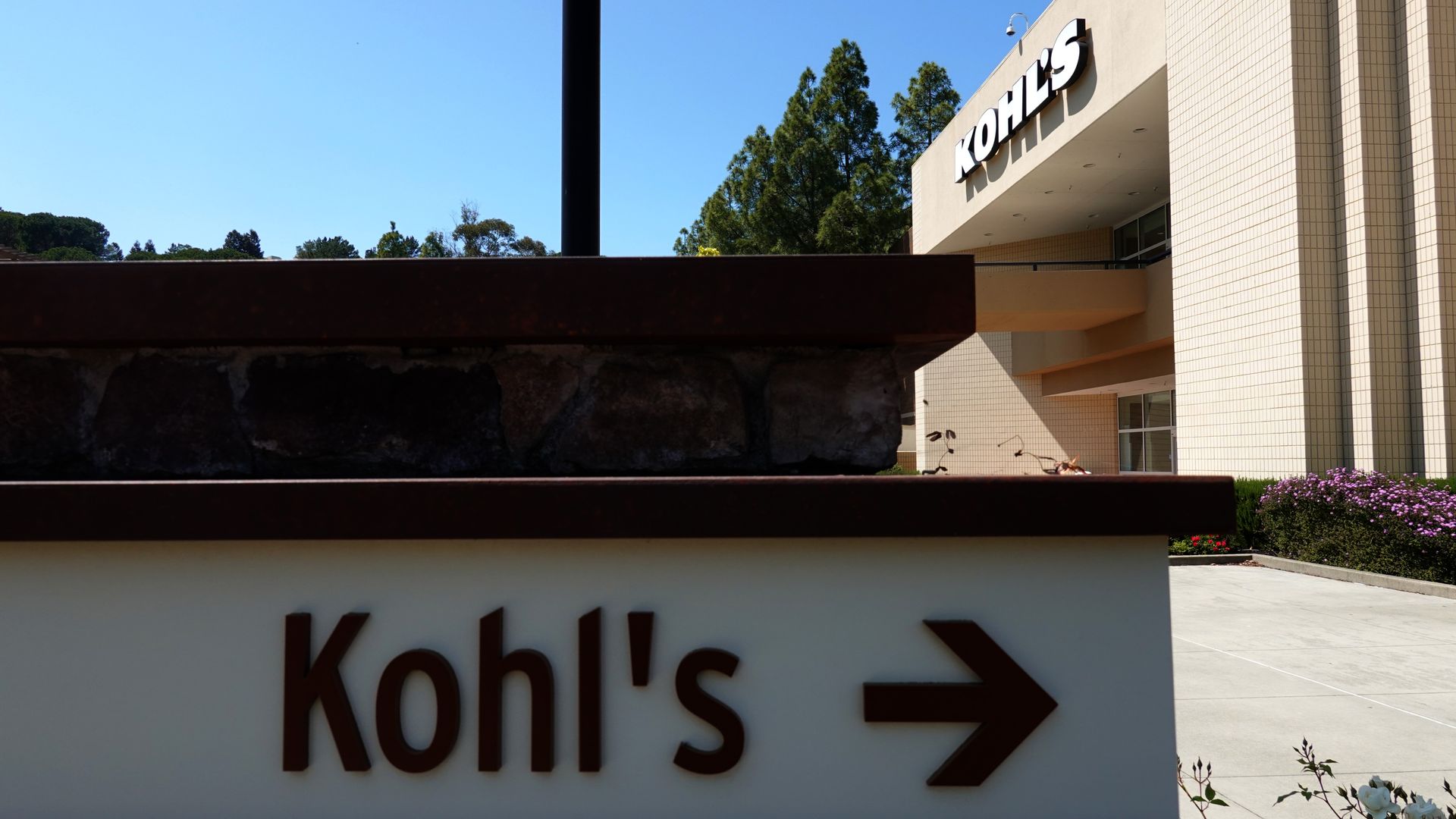 The Kohl's name is spelled out on the side of a building in brown lettering alongside an arrow pointing to the right.