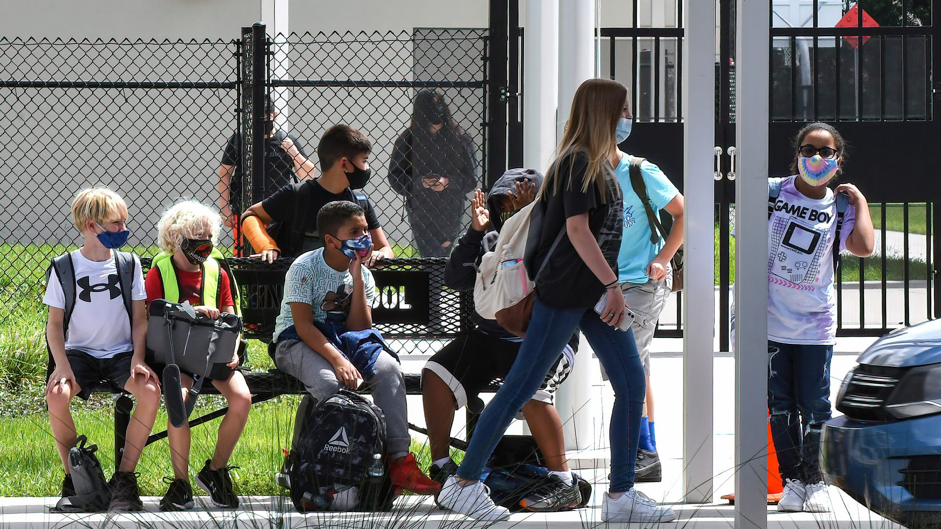 Students wearing face masks wait to be picked up by their parents at Pershing School in Orlando.