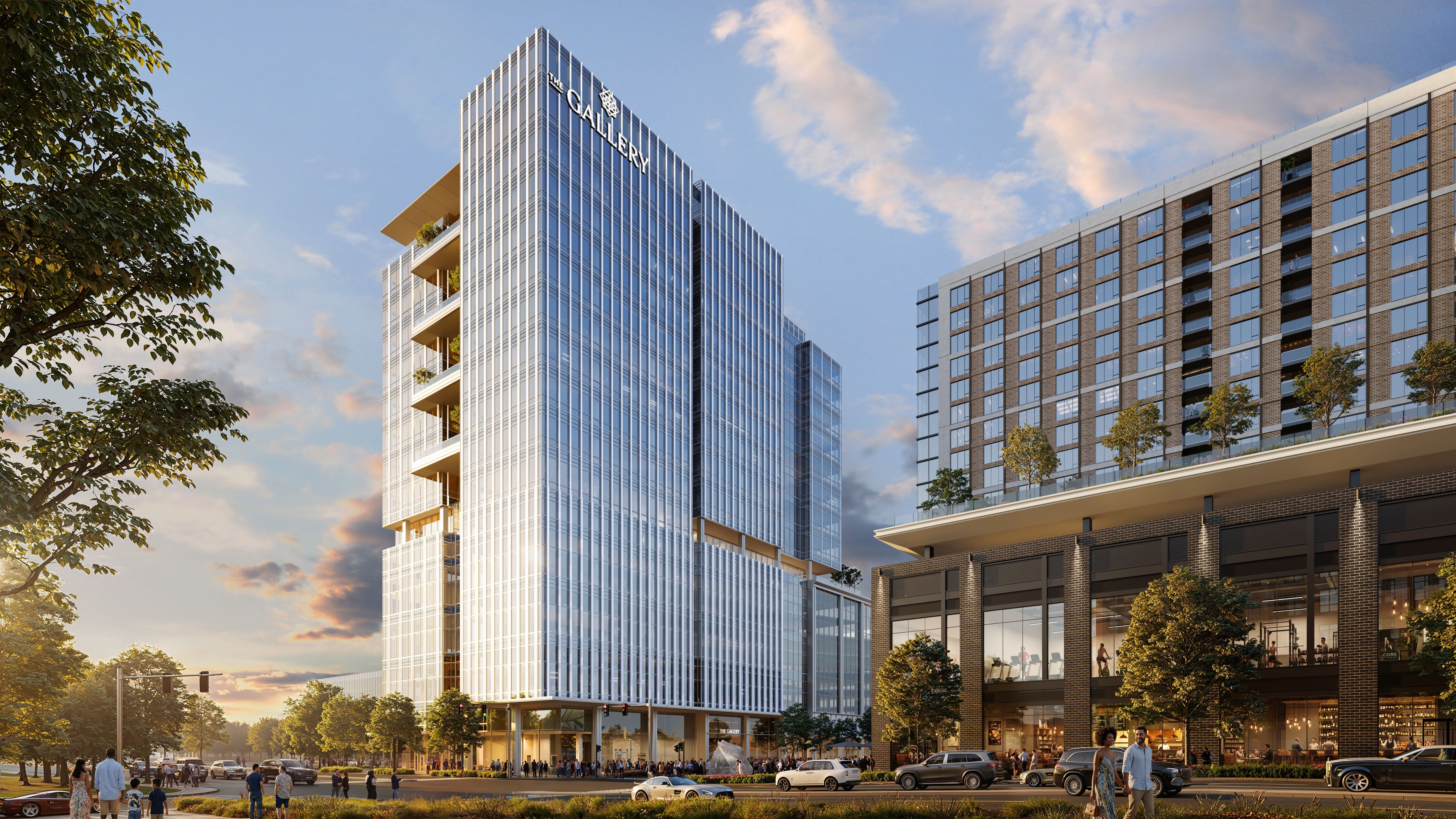 Modern glass skyscraper complex labeled "The Gallery," with blue-tinted windows, balconies, and a brick building to the right; trees, pedestrians, and cars along a sunny urban street.