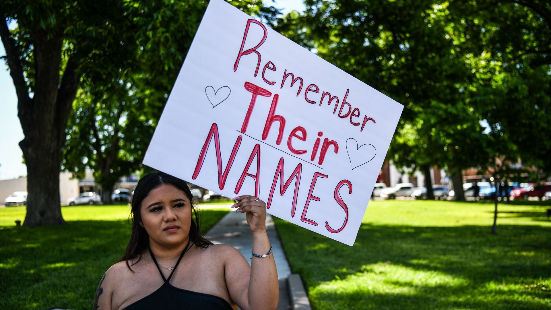 A woman in Uvalde, Texas, holds a sign that reads "remember their names" written in red, after the shooting there that left 19 kids and two teachers dead