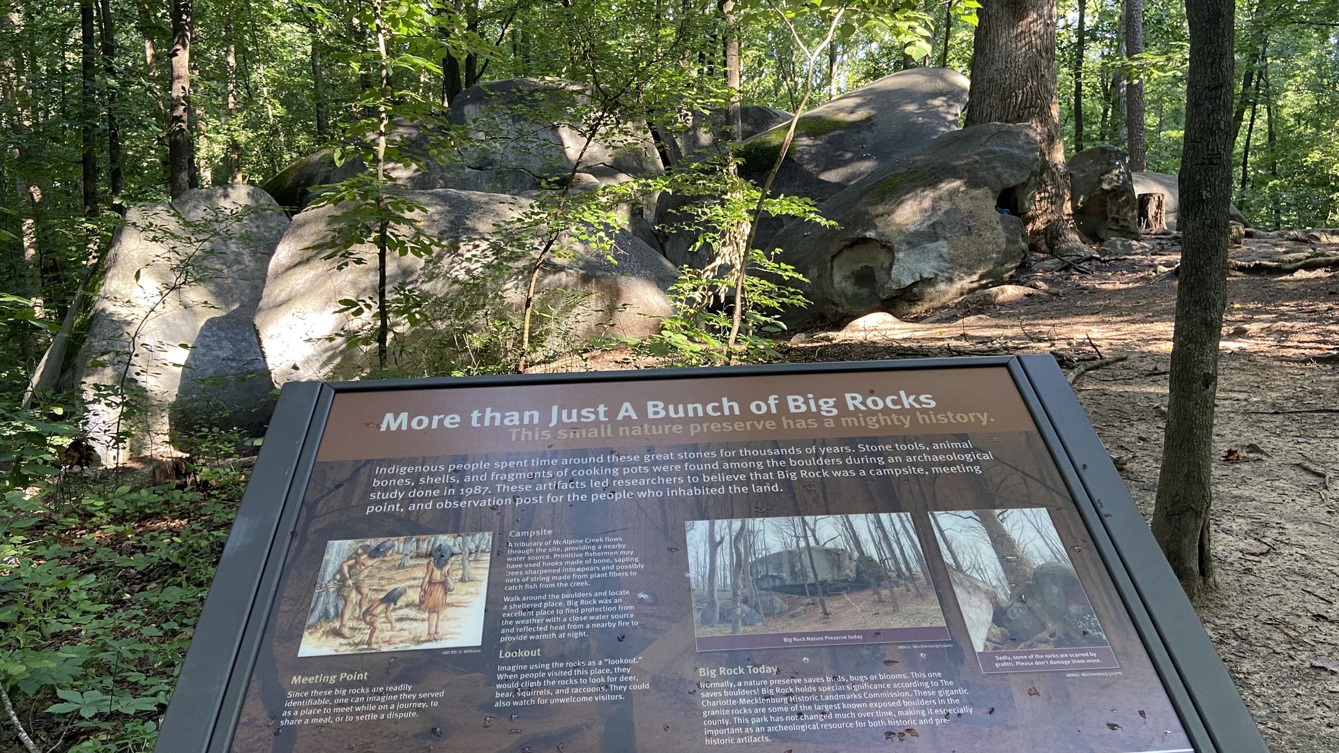 Information board titled "More than Just A Bunch of Big Rocks" in a forested area with large granite boulders and trees in the background, explaining the history and significance of the Big Rock Nature Preserve.