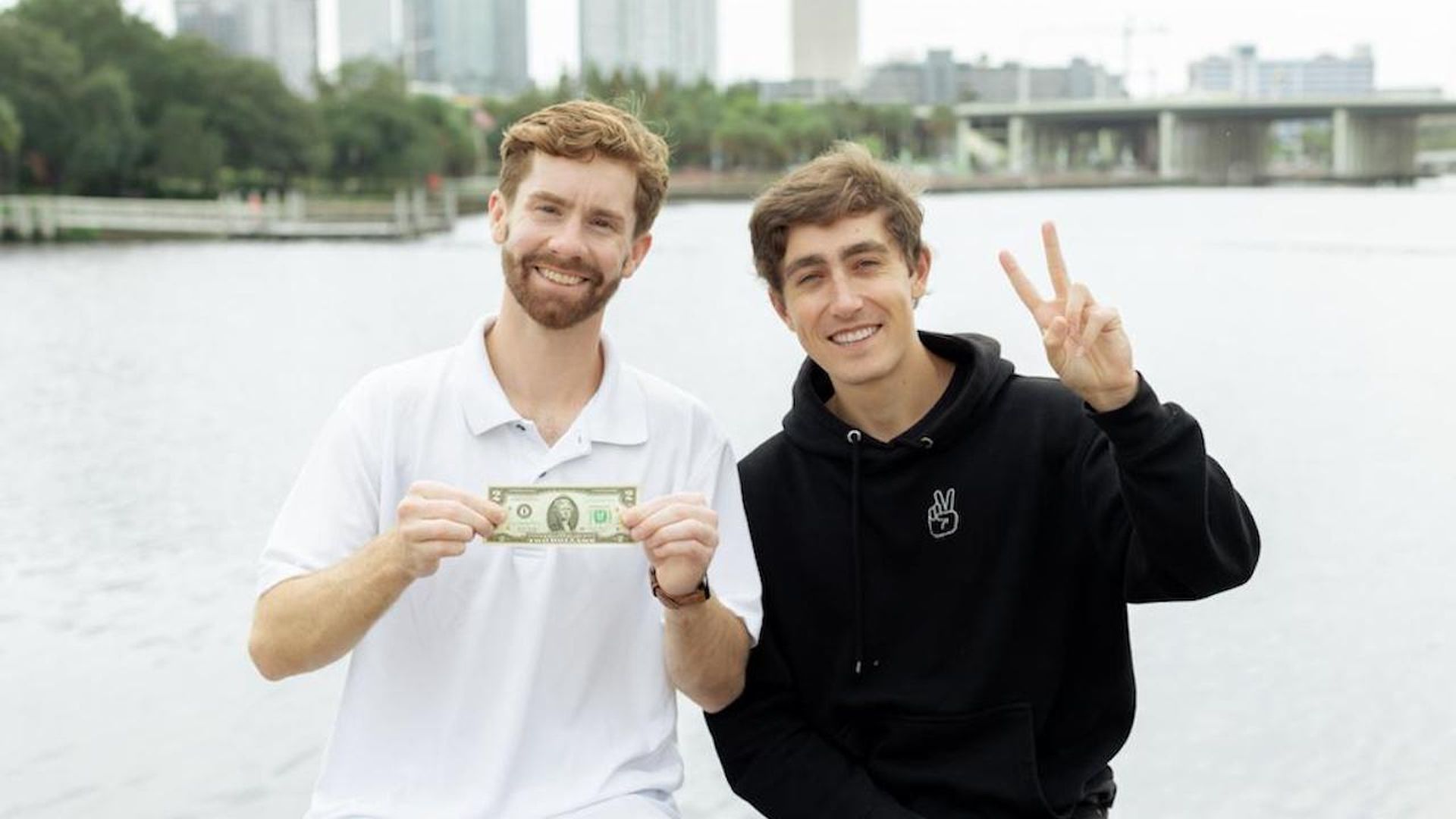 Joe holding a $2 bill and Parker holding up a peace sign in downtown Tampa