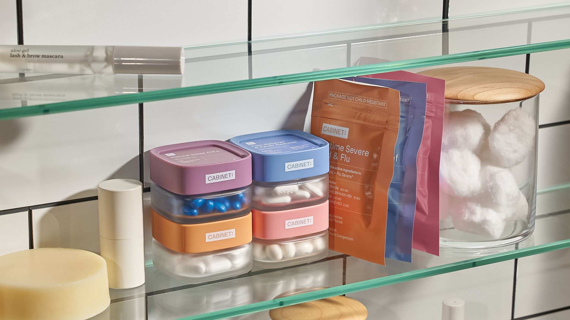 A stack of clear glass containers sits on a glass shelf in a bathroom.