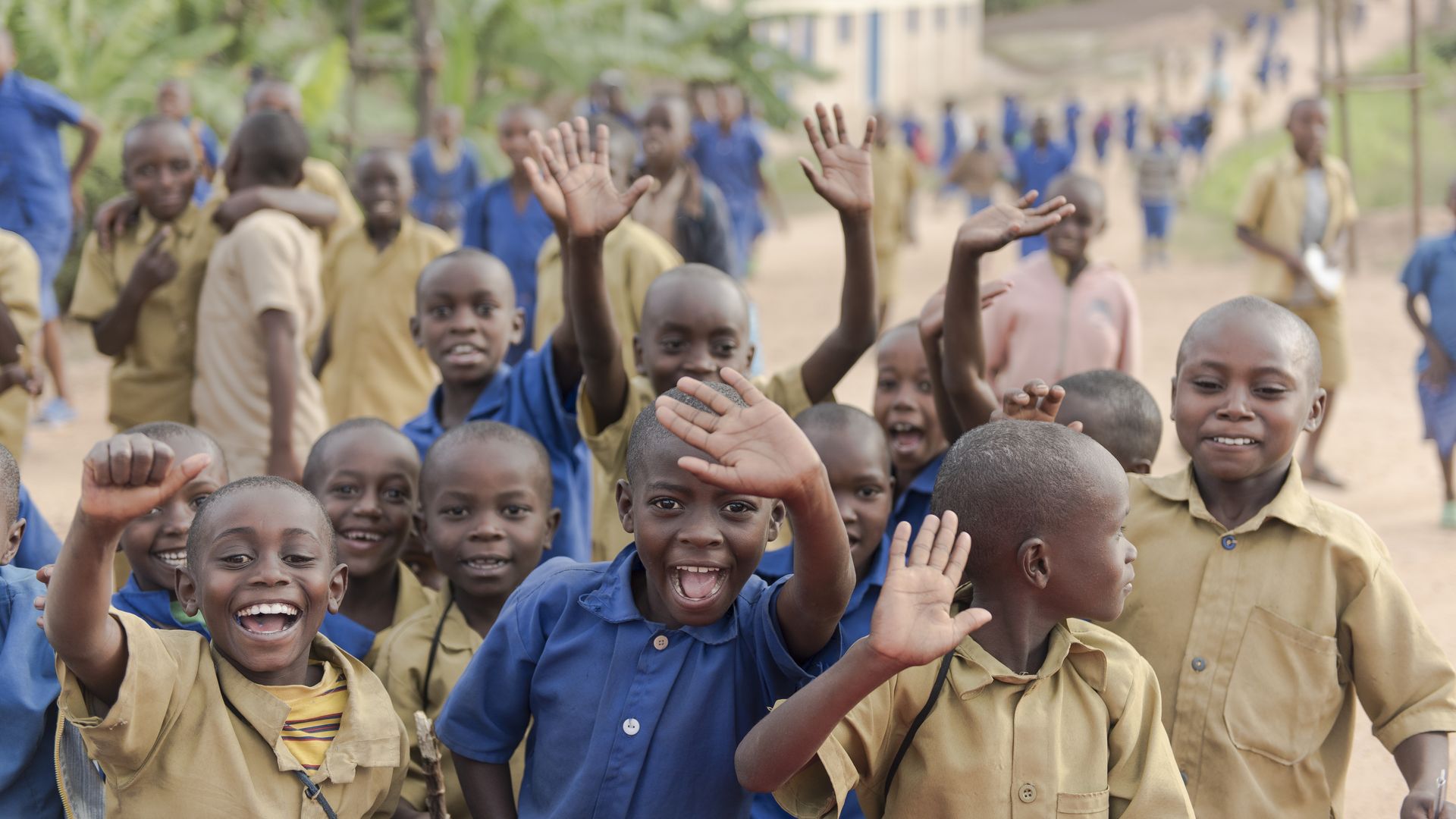 Primary school children wave after school in the Kyaumbu Sector of Rwanda. 