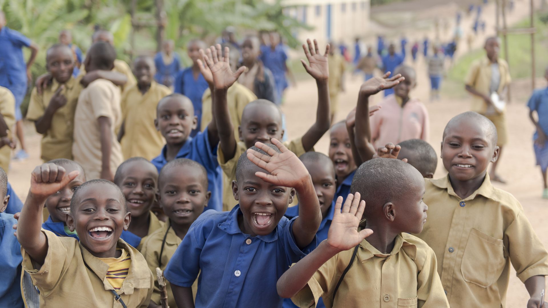 Primary school children wave after school in the Kyaumbu Sector of Rwanda.