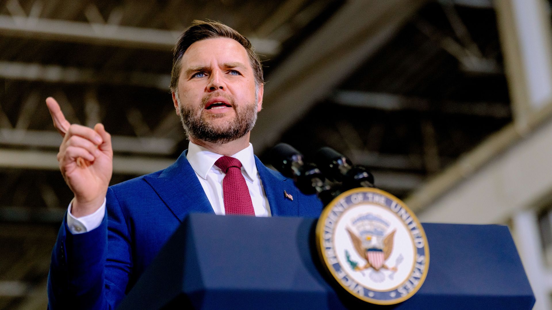 JD Vance speaks behind a podium and points.