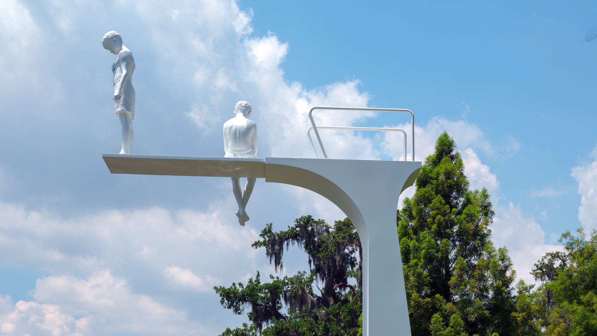 Photo shows a sculpture of two people on top of a diving board.