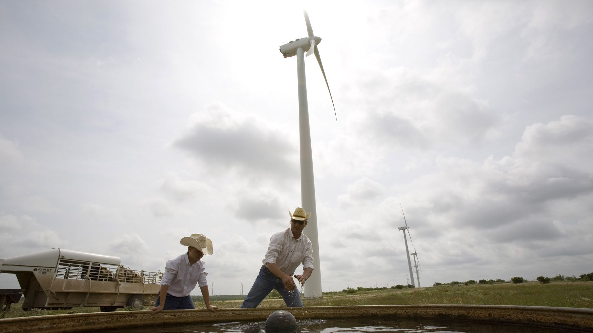 A father and son clean a water tank for their cattle on a wind farm north of Abilene