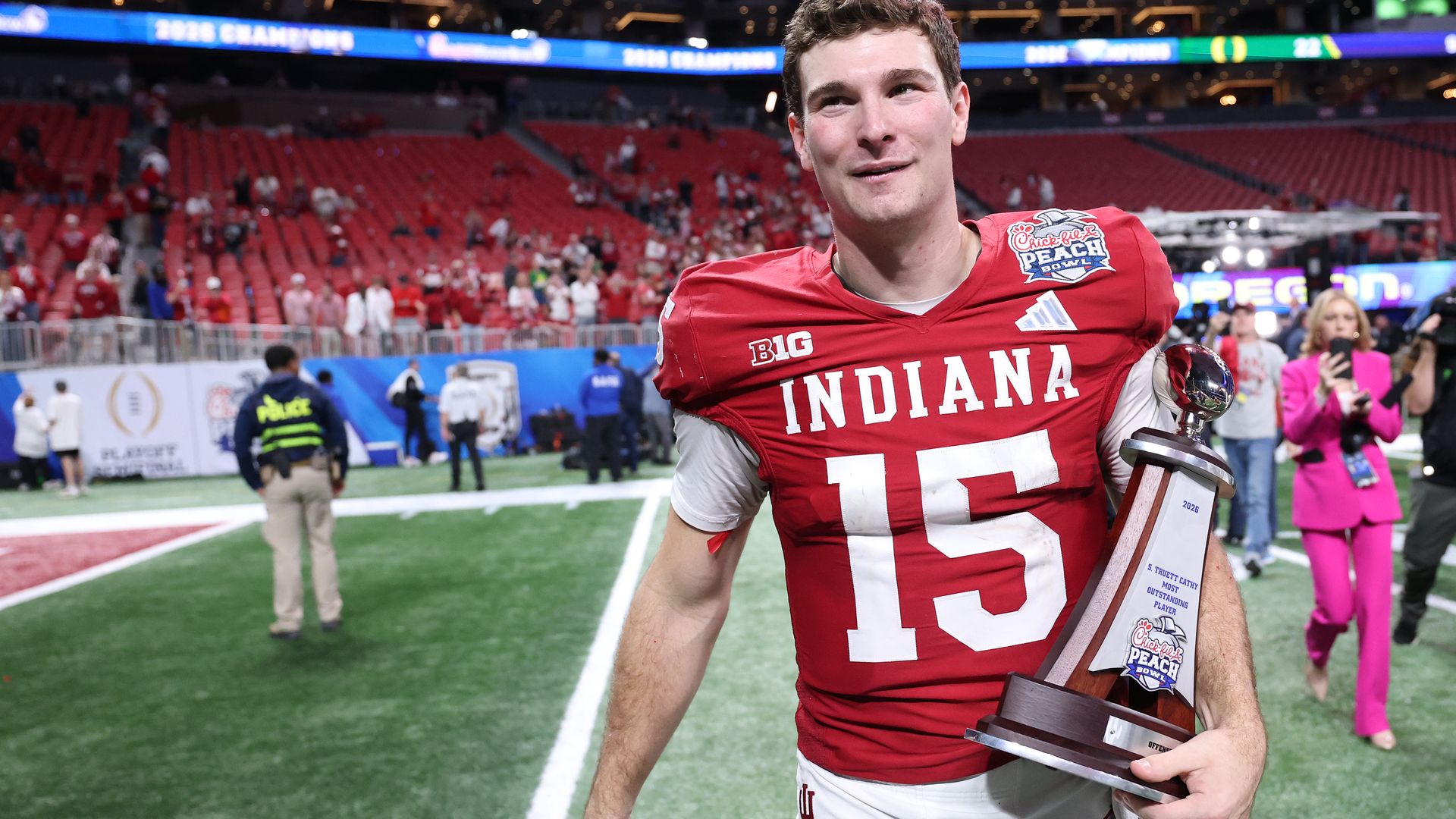 Indiana's Fernando Mendoza clutching a trophy at the Chick-fil-A Peach Bowl at Mercedes-Benz Stadium.