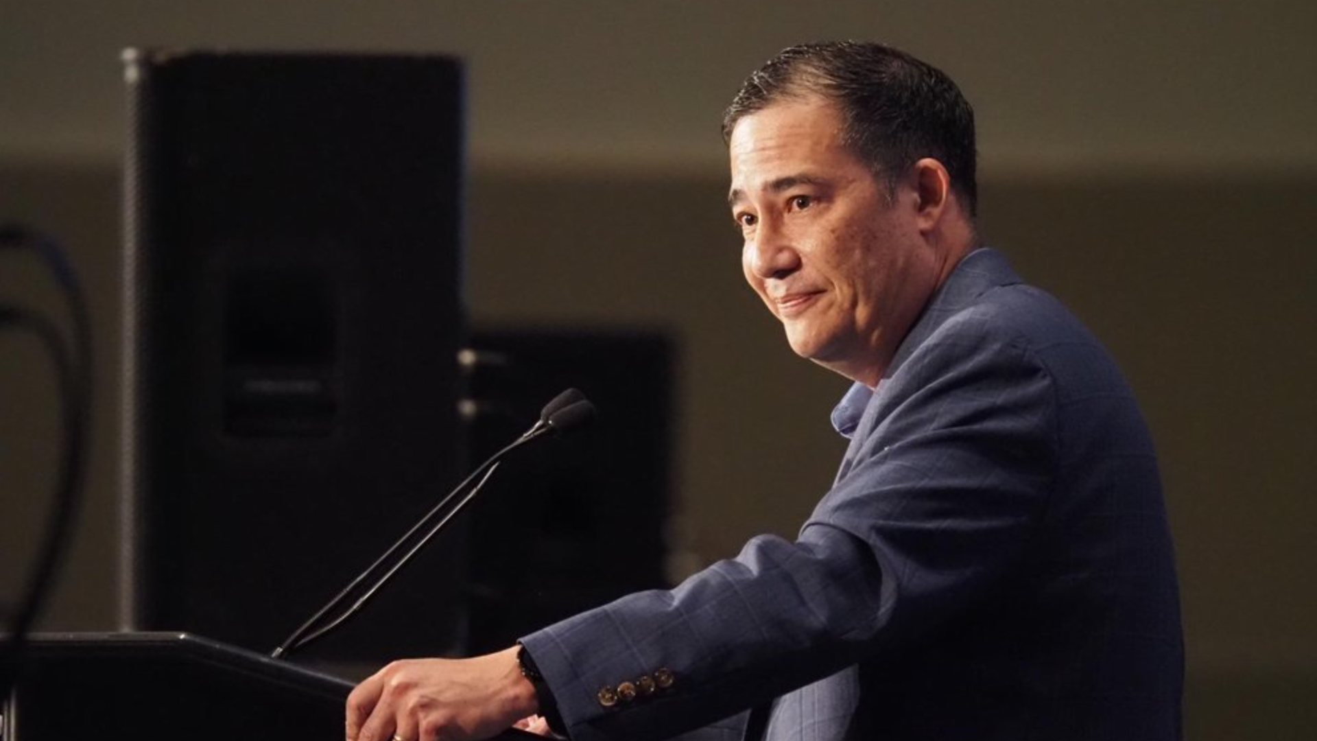 A man stands at a podium looking over to one side. 