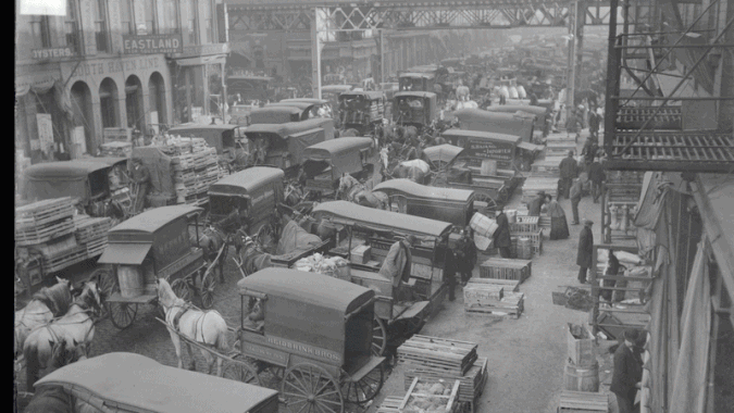 A GIF that shows an old street with wagons dissolving into a modern street with a train running above it. 