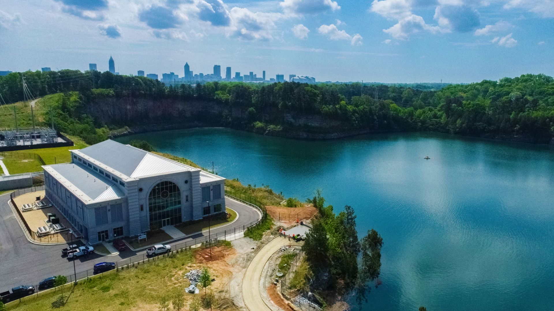 A building overlooks a giant reservoir with the Atlanta skyline in the background