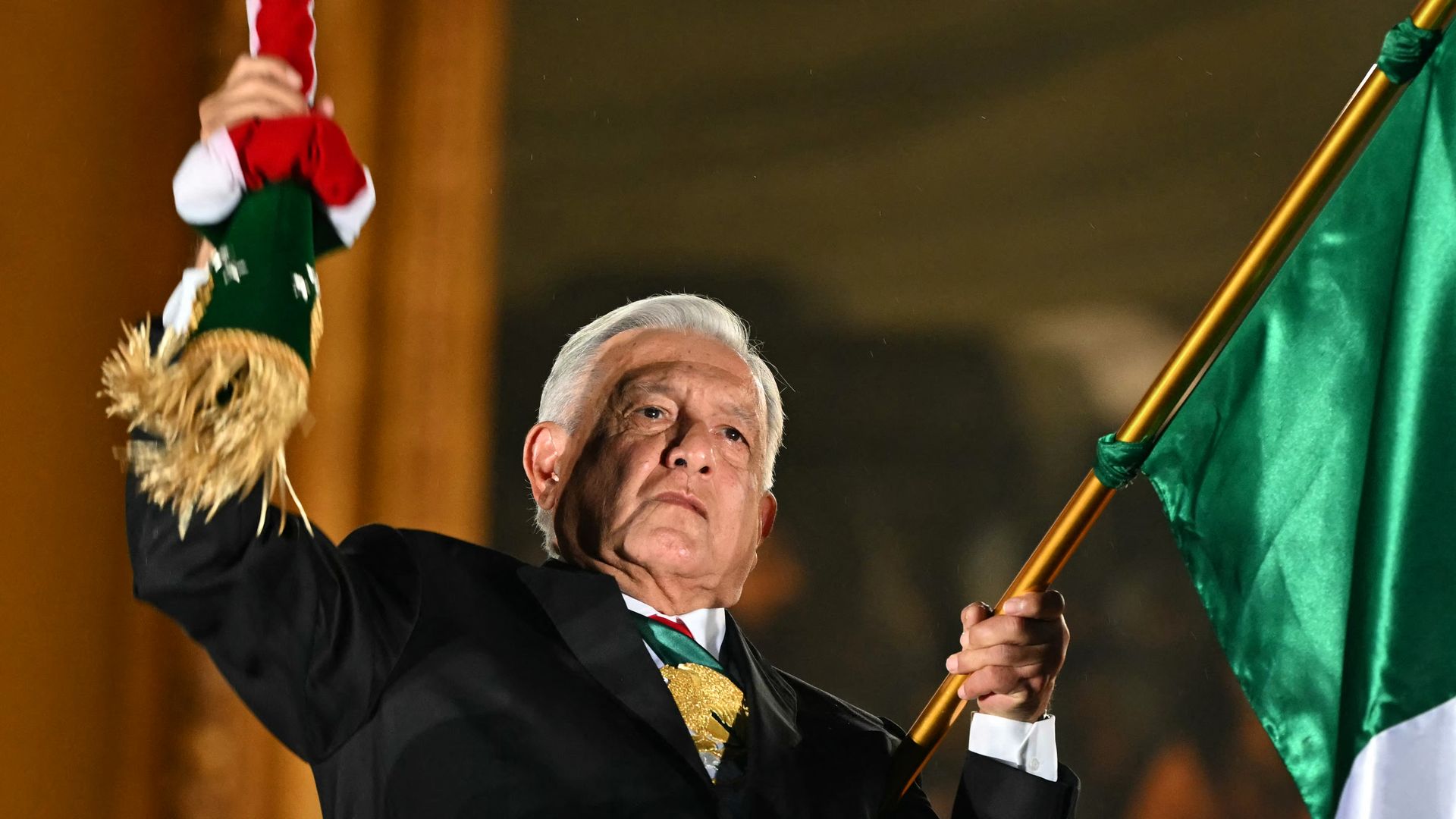 Mexican President Andres Manuel Lopez Obrador raises a large Mexican flag