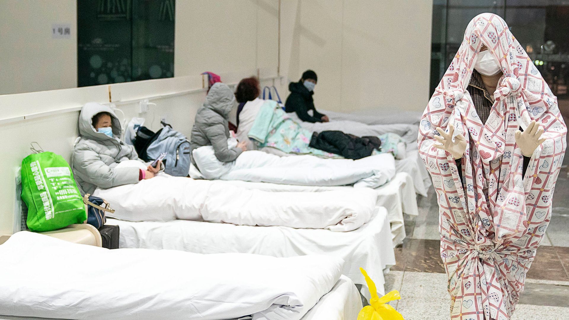 A patient (R) covered with a bed sheet at a converted hospital as it starts to accept patients displaying mild symptoms of the novel coronavirus in Wuhan in China's central Hubei province. 