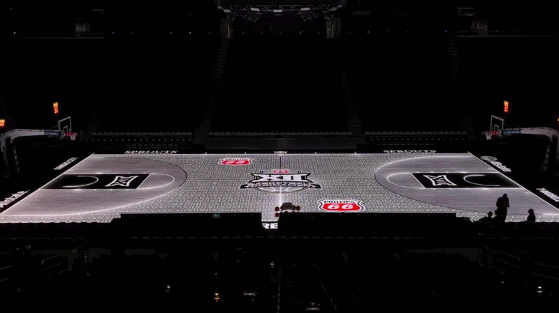 A basketball court in an empty arena flashes different colors and the lines glow white as "XII" flashes in white in the background.
