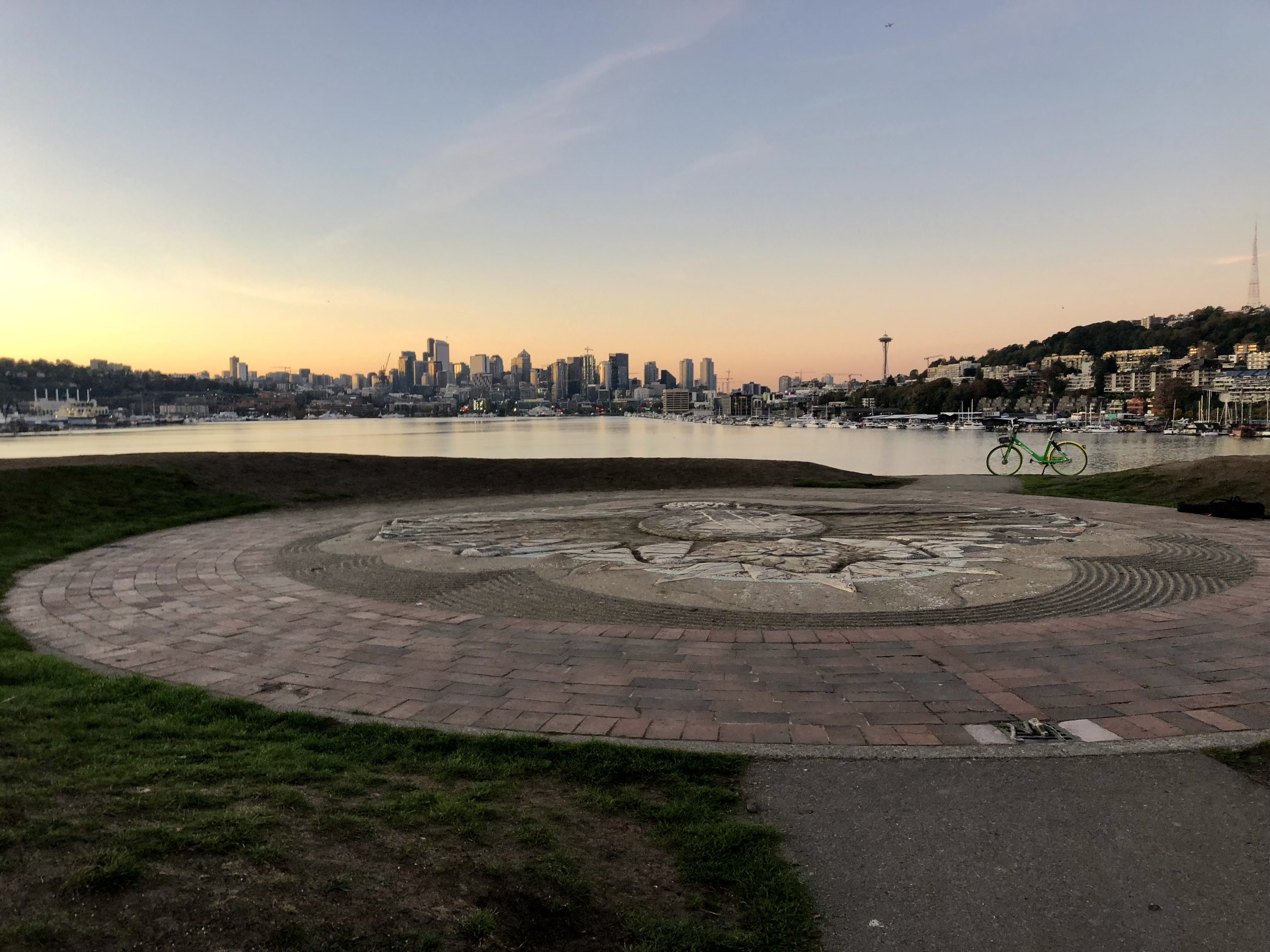 Sunset over the Seattle skyline, seen over Lake Union, with the hill and mosaic artwork at Gas Works Park in the foreground.