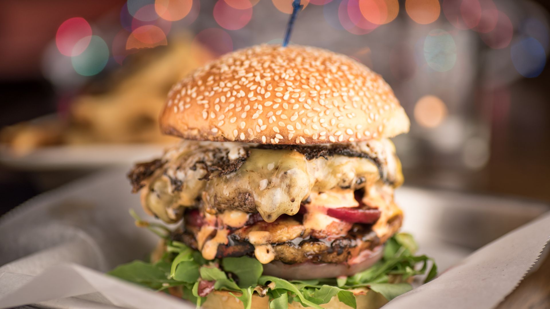 A double cheeseburger with a sesame bun, grilled onion and arugula