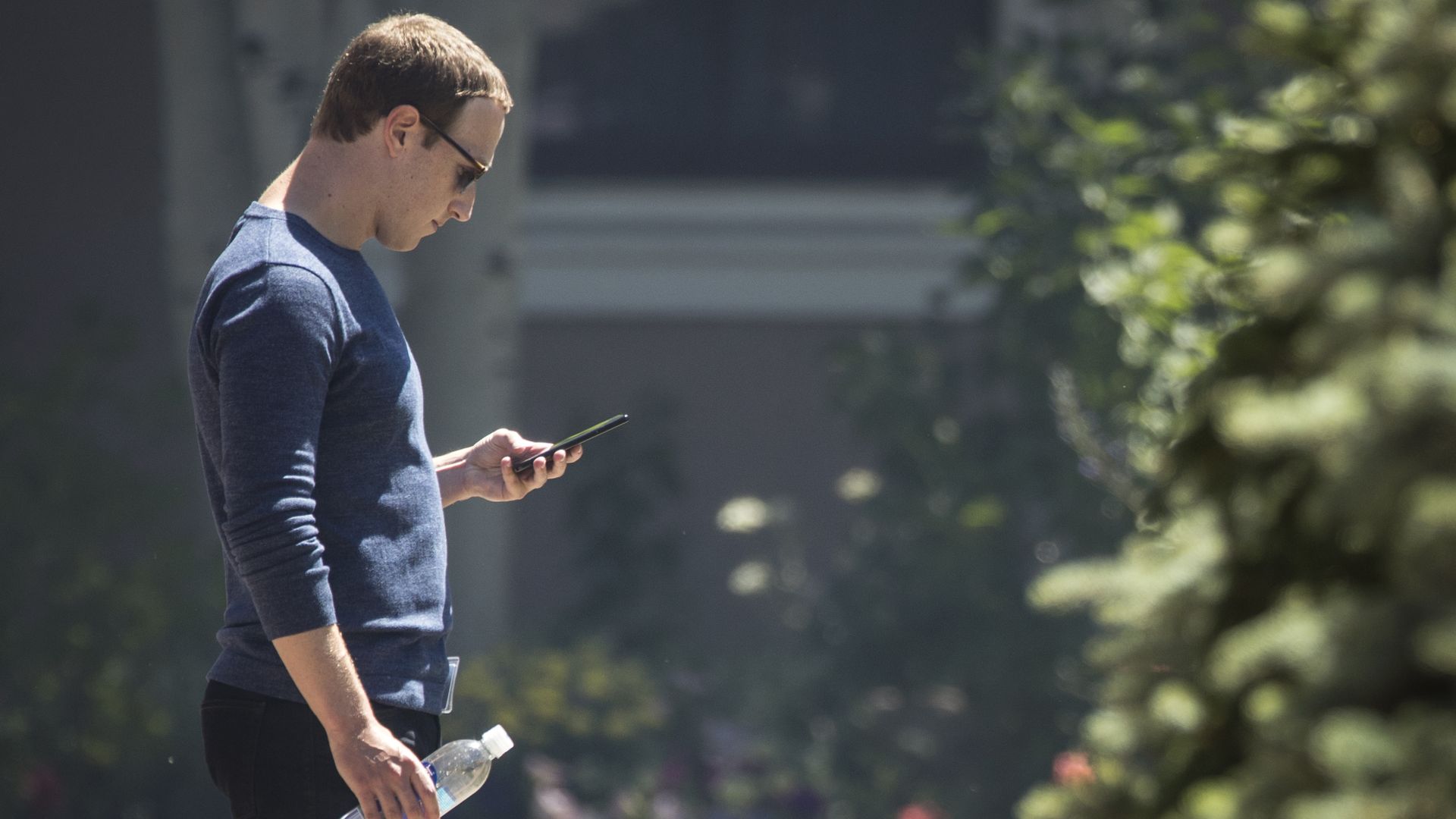 Mark zuckerberg looks at his phone outside
