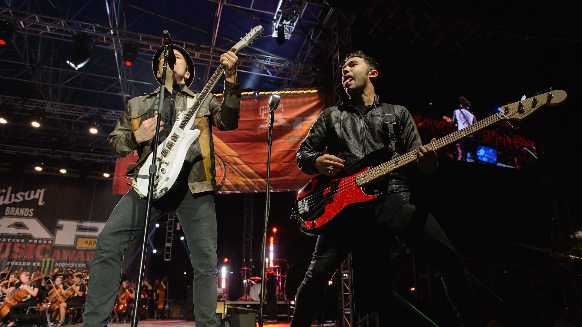 Two members of Fall Out Boy perform on stage. 
