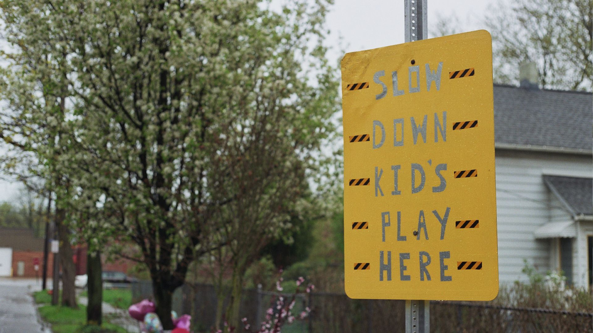 A yellow handmade sign reading, "Slow down, kids play here" 