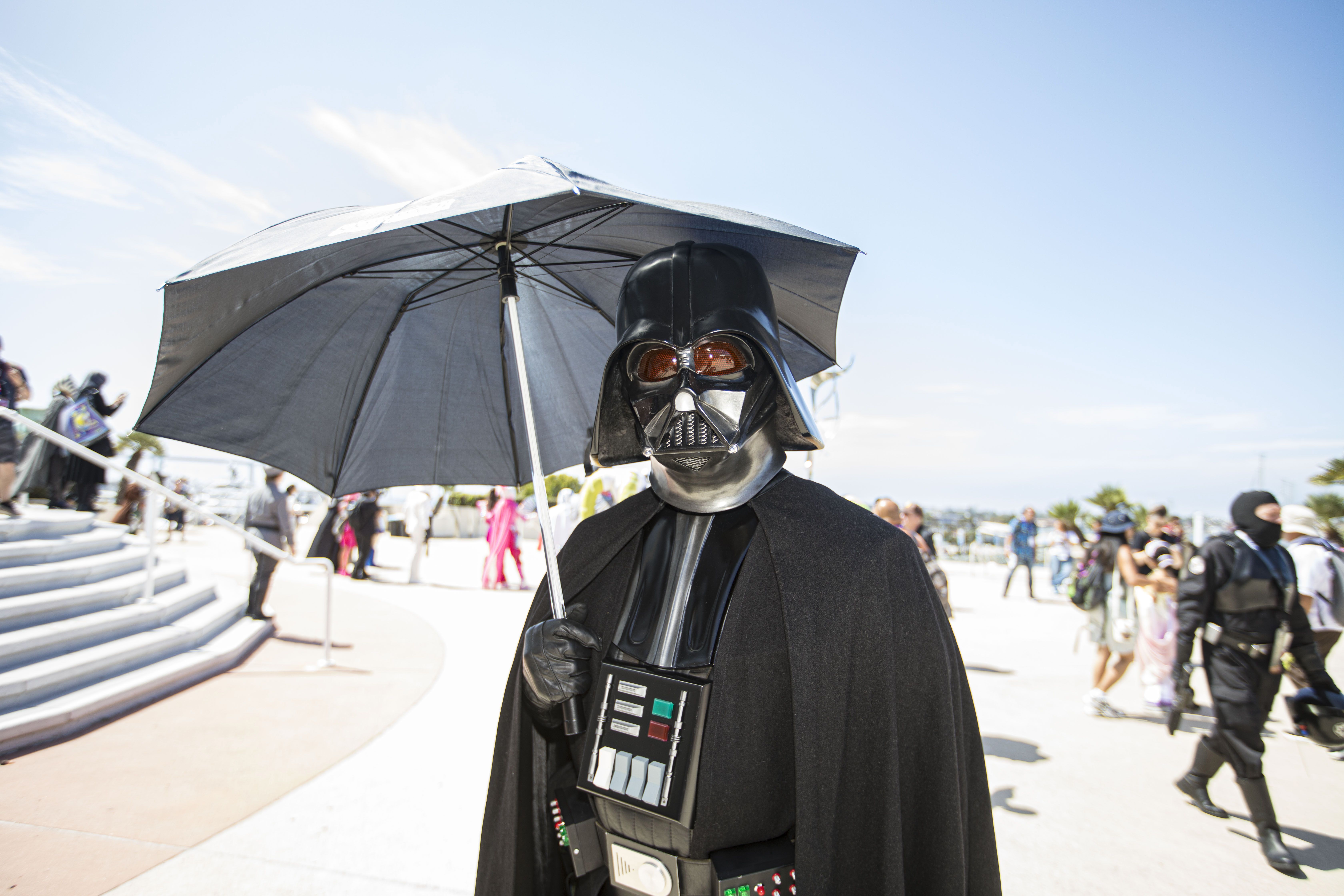 A Comic-Con attendee dressed as Darth Vader stands in full black armor and helmet during the convention in San Diego.