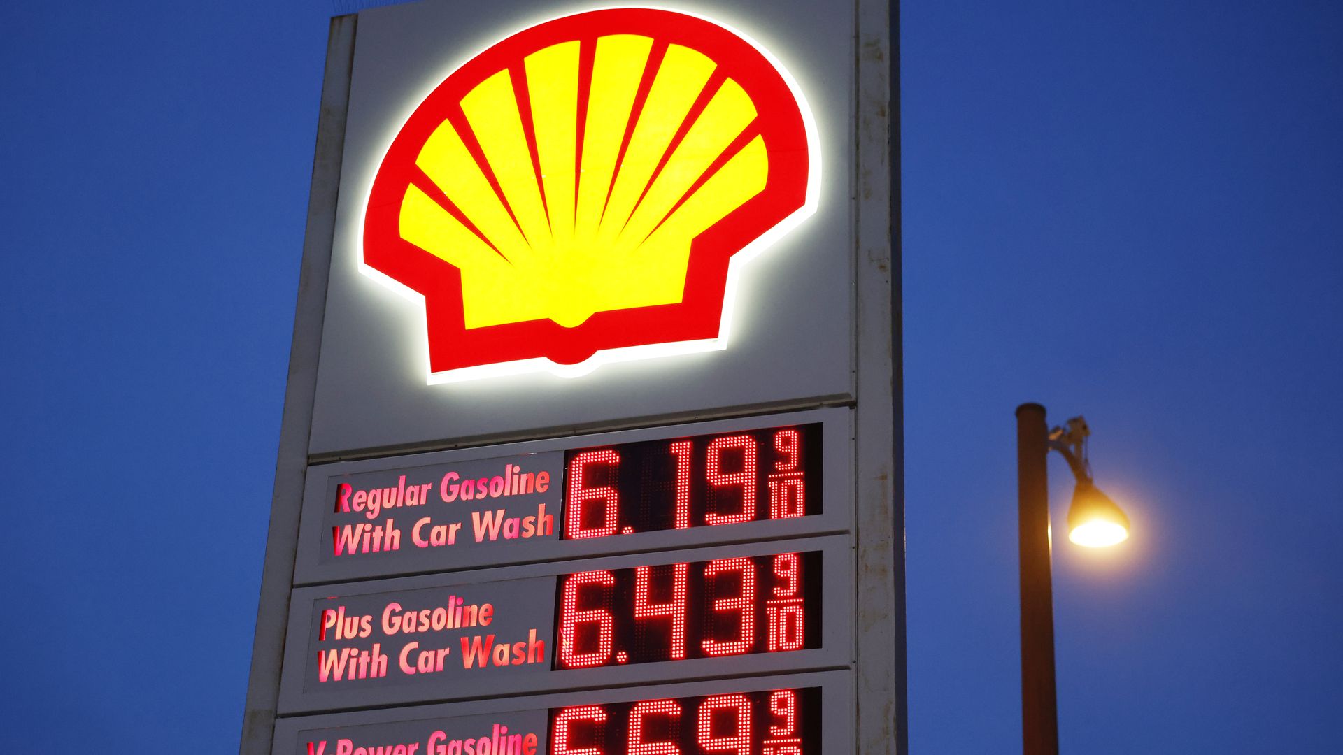 A Shell gas station sign in Pasadena shows high gasoline prices, with fuel pumps and cars visible beneath the canopy.
