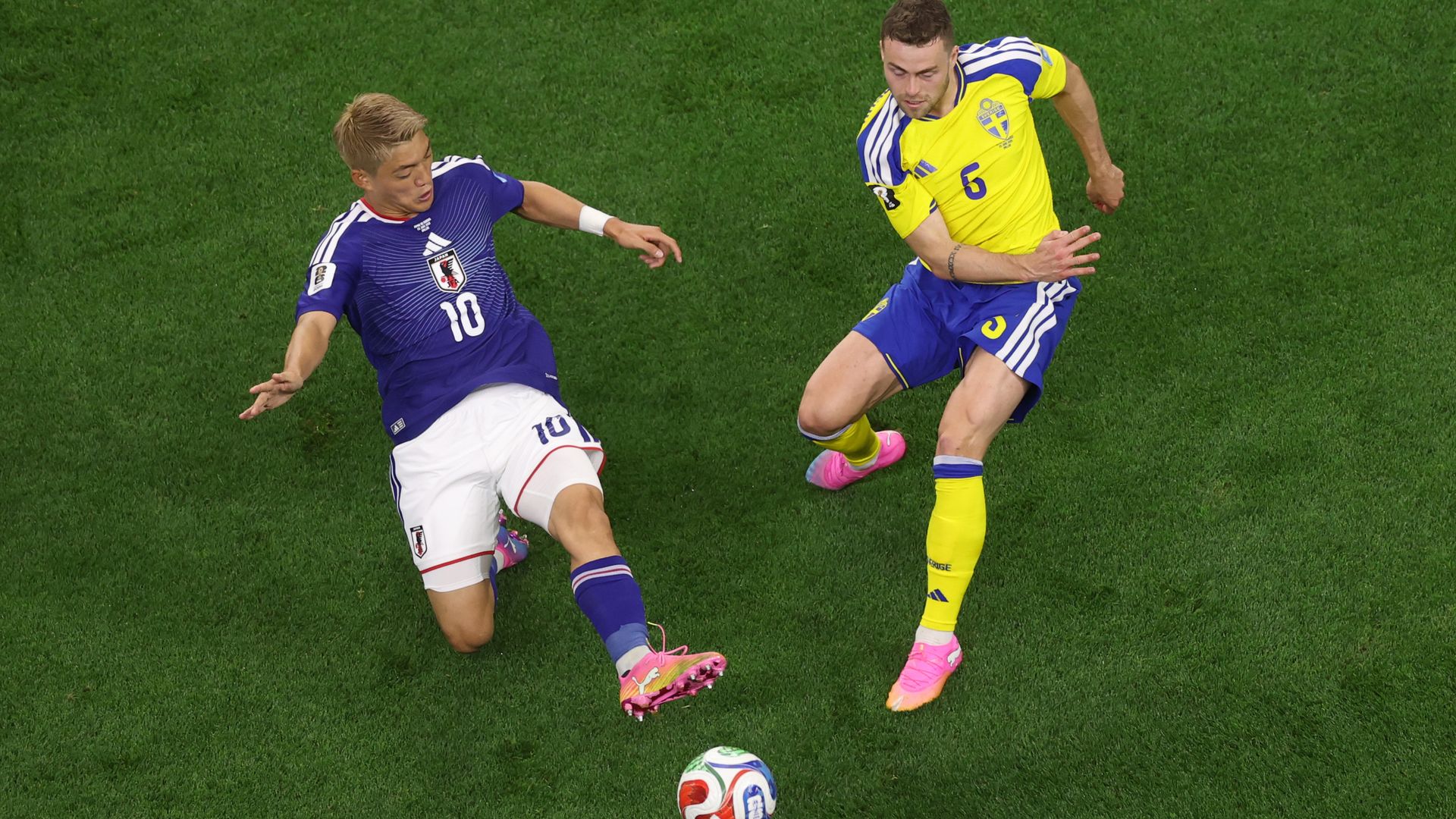 A Sweden player and a Japan player go toe-to-toe on the field 