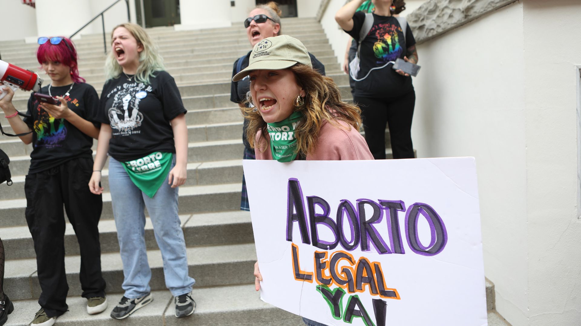 A woman yells while holding a sign that reads "Aborto legal ya!"