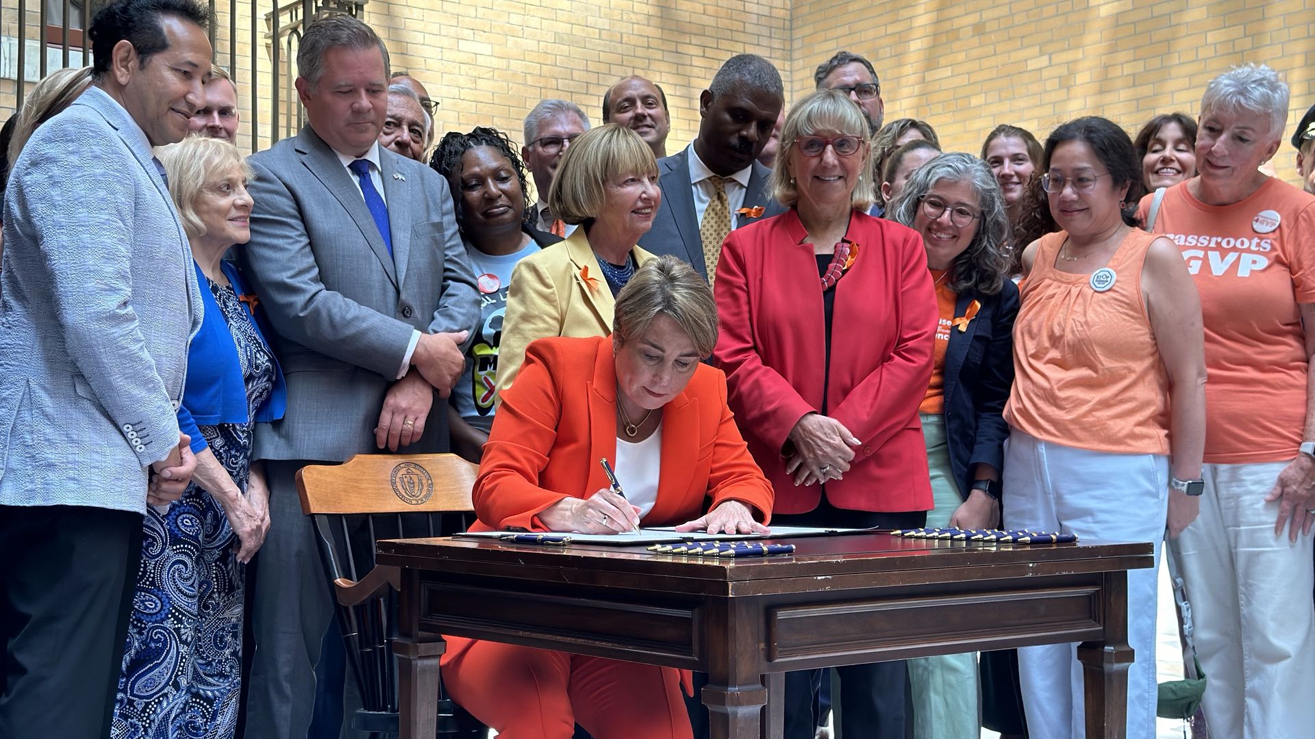Massachusetts Gov. Maura Healey surrounded by legislators and gun safety advocates as she signs a gun reform bill in the State House.