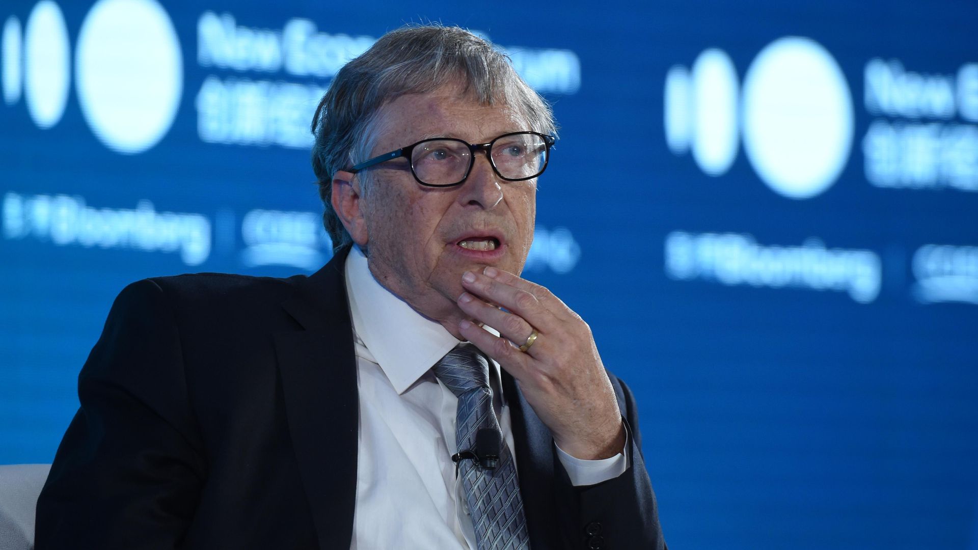 In this image, Bill Gates sits in a suit and talks