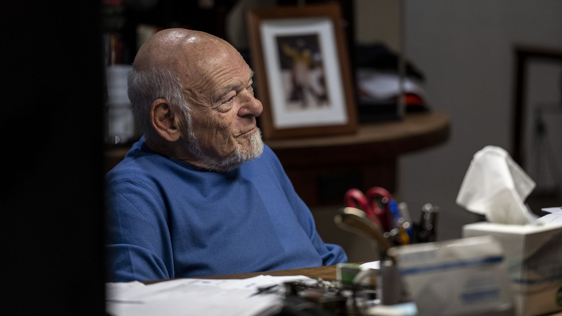 A man in a blue shirt sits at a desk
