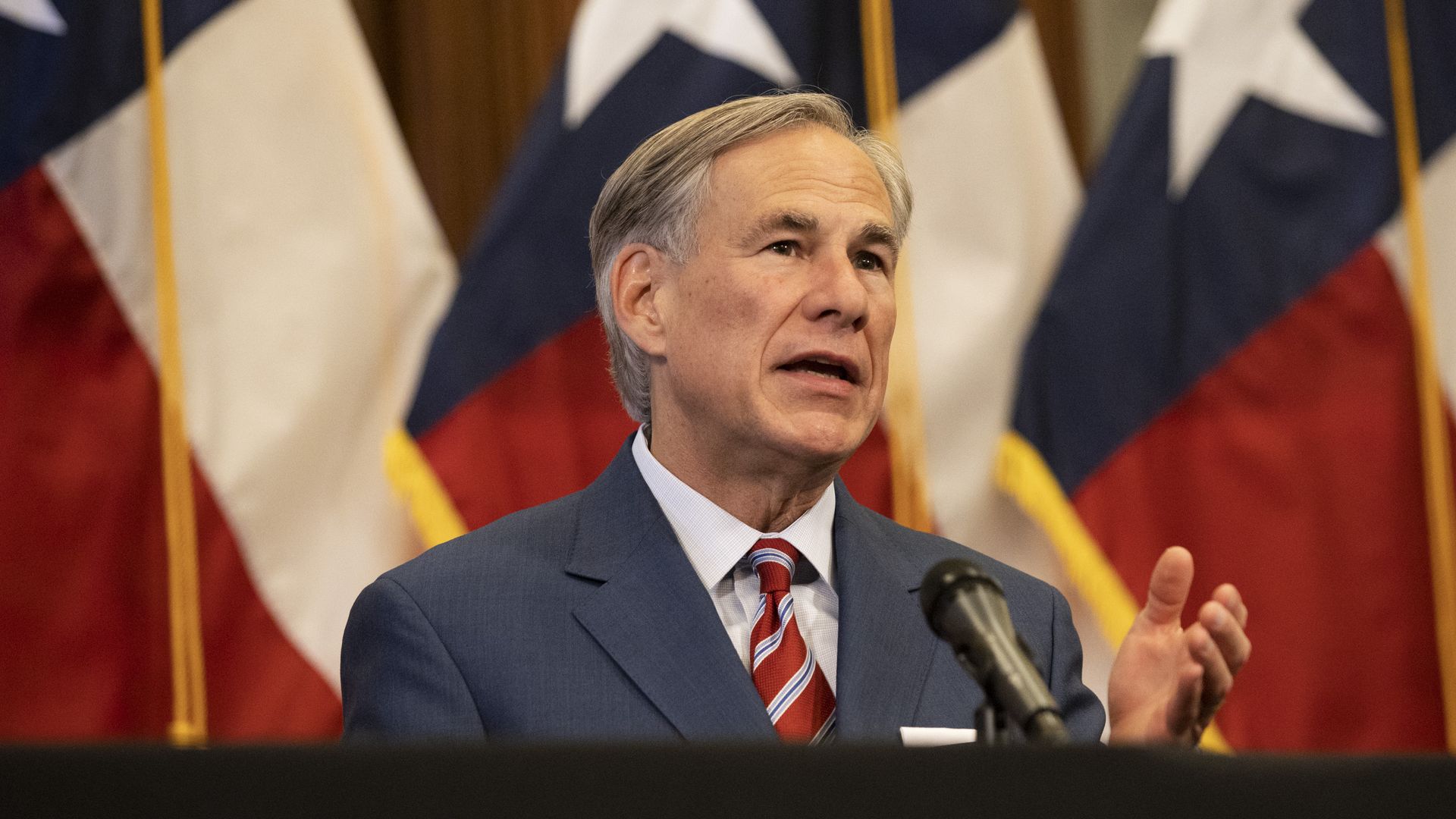 Photo of Greg Abbott in a suit speaking and gesturing with one hand