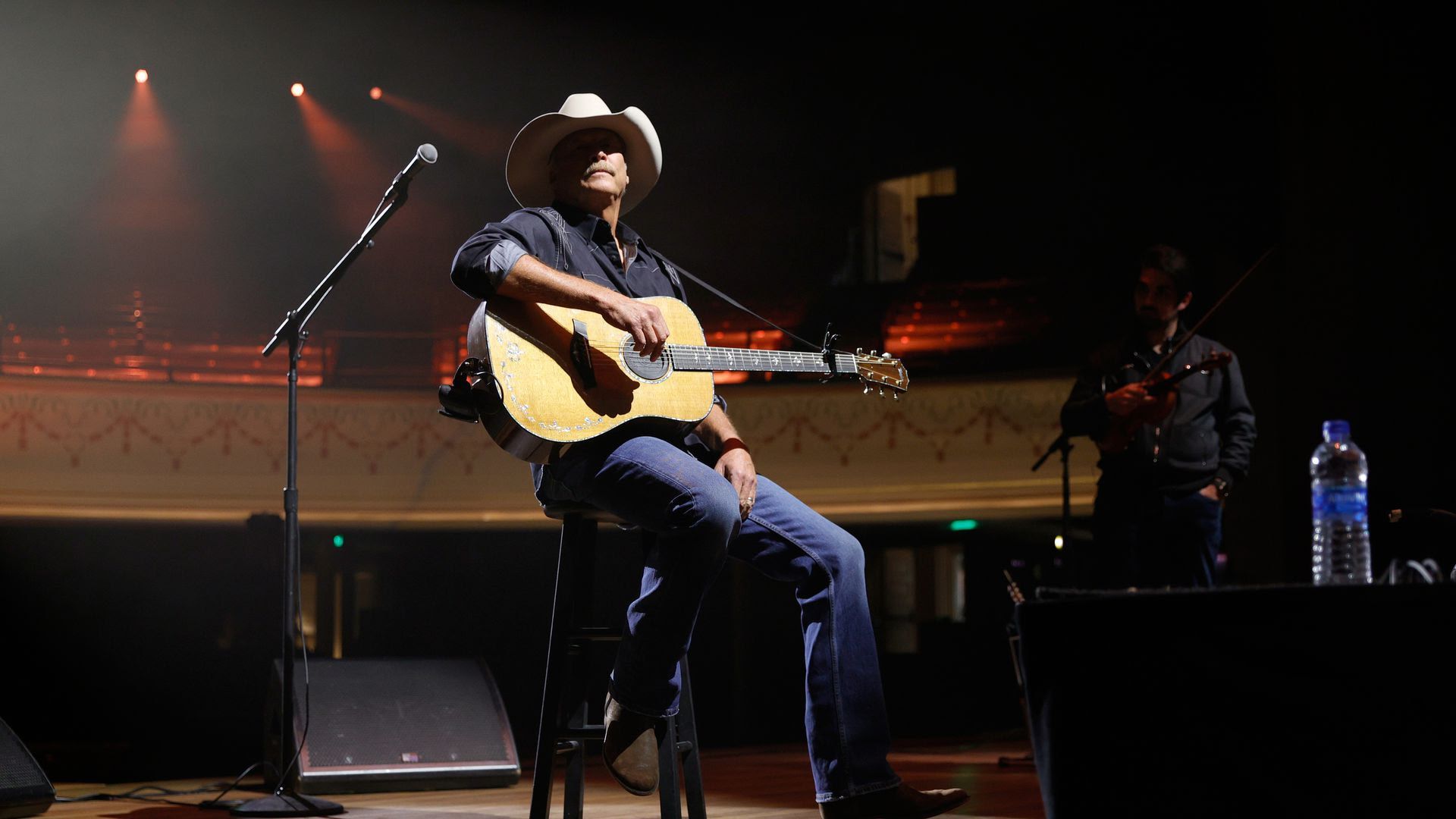 Alan Jackson wears a white cowboy hat while playing the guitar on stage in May 2021.