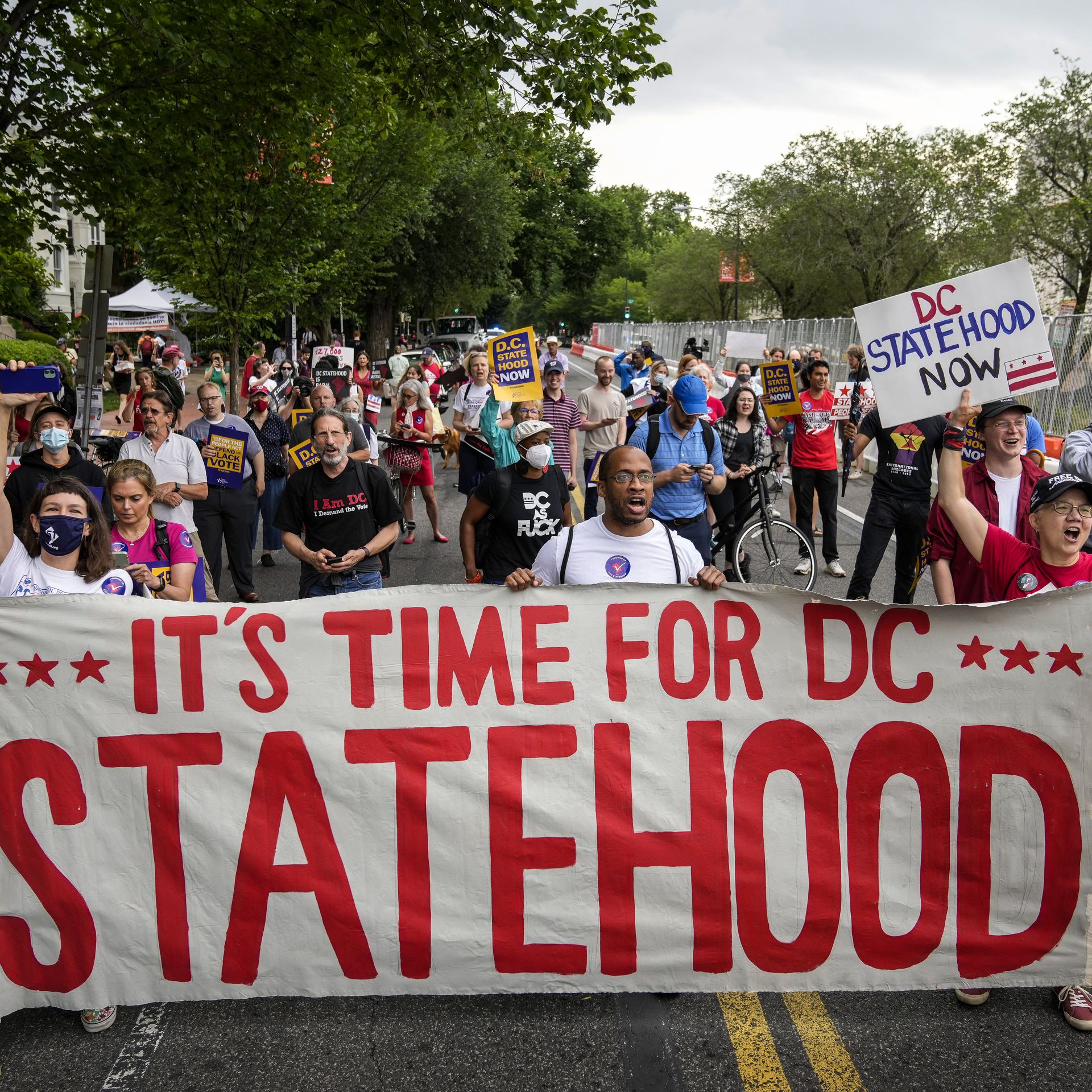 A group of D.C. statehood supporters carry a large banner and march down a street