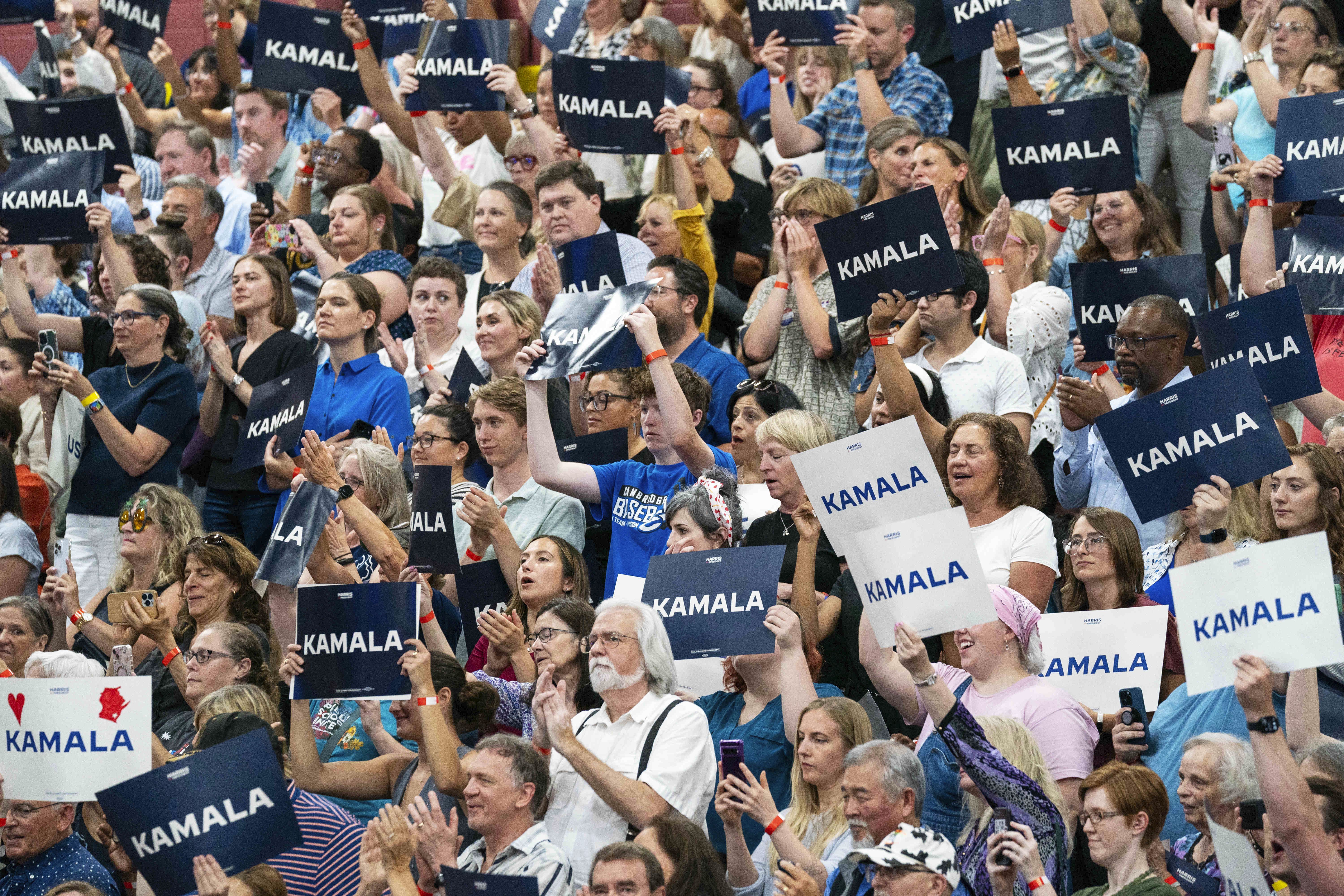 Supporters hold up "Kamala" signs during a rally at West Allis Central High School near Milwaukee yesterday.