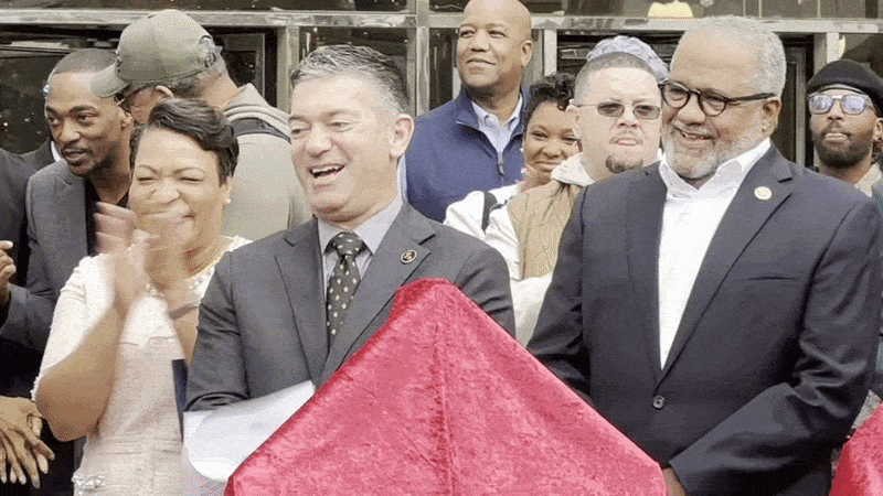 Michael Hecht stands among dignitaries, including former Mayor LaToya Cantrell and Congressman Troy Carter, and applauds.