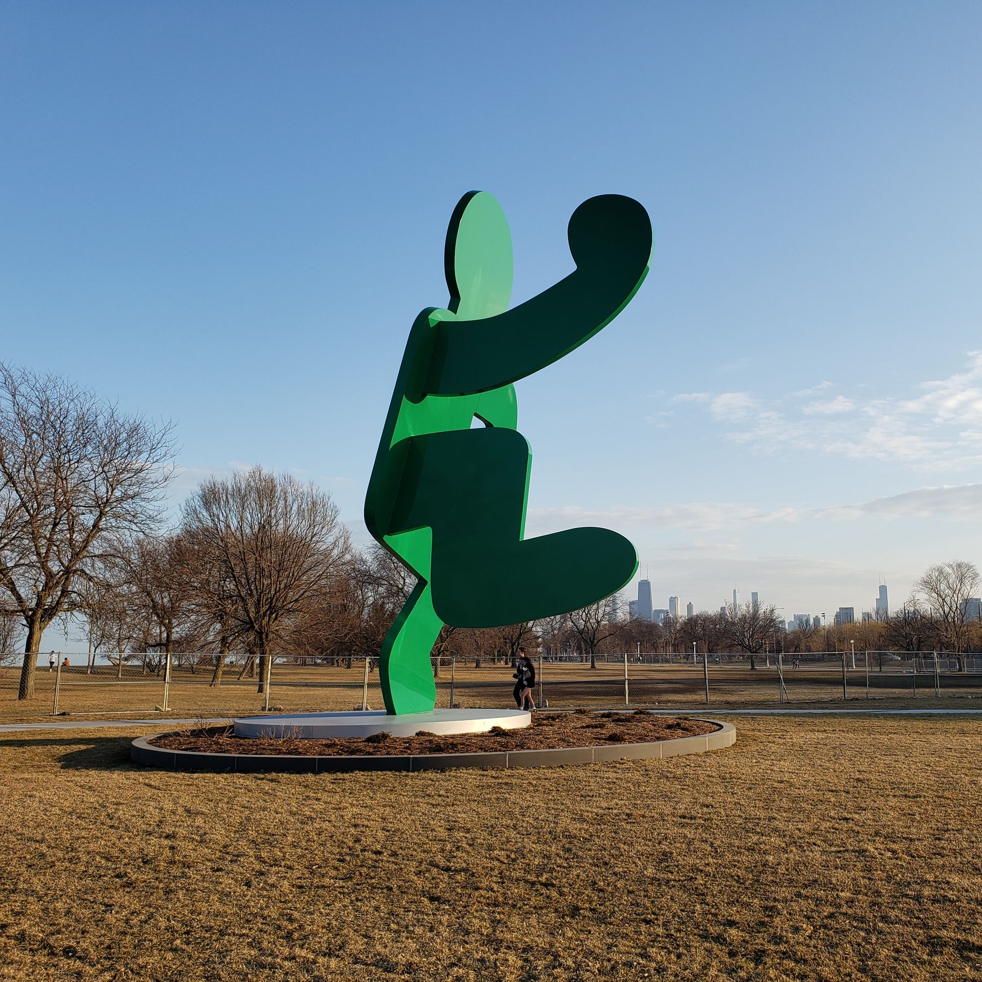 Photo of a green body scultpure in a park with the Chicago skyline behind it. 