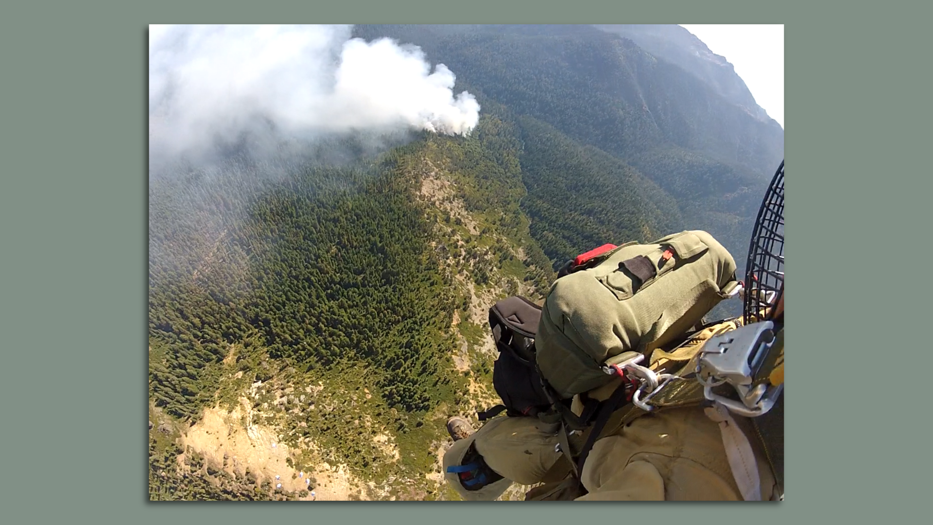 A person descends onto a wildfire on a forest hillside.