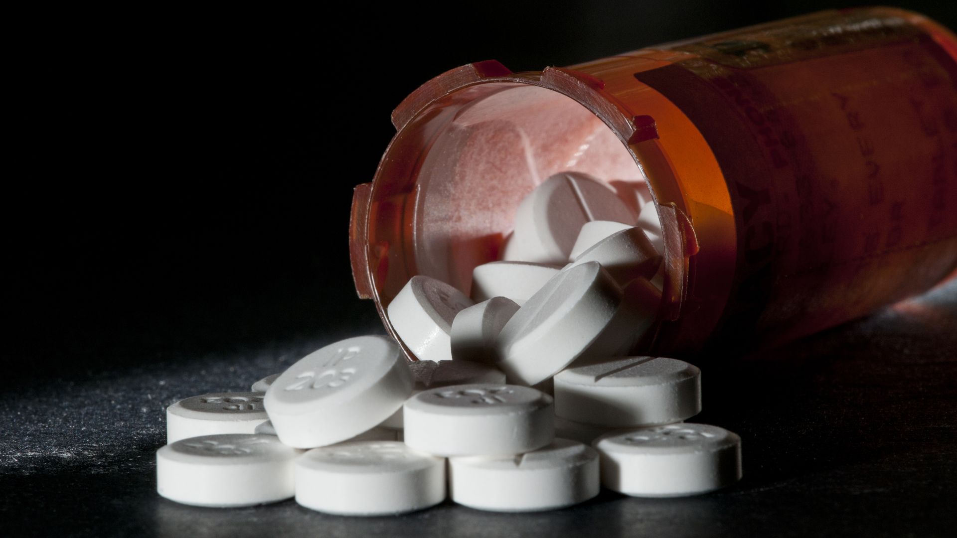 A bottle of pills, spilling out onto a table