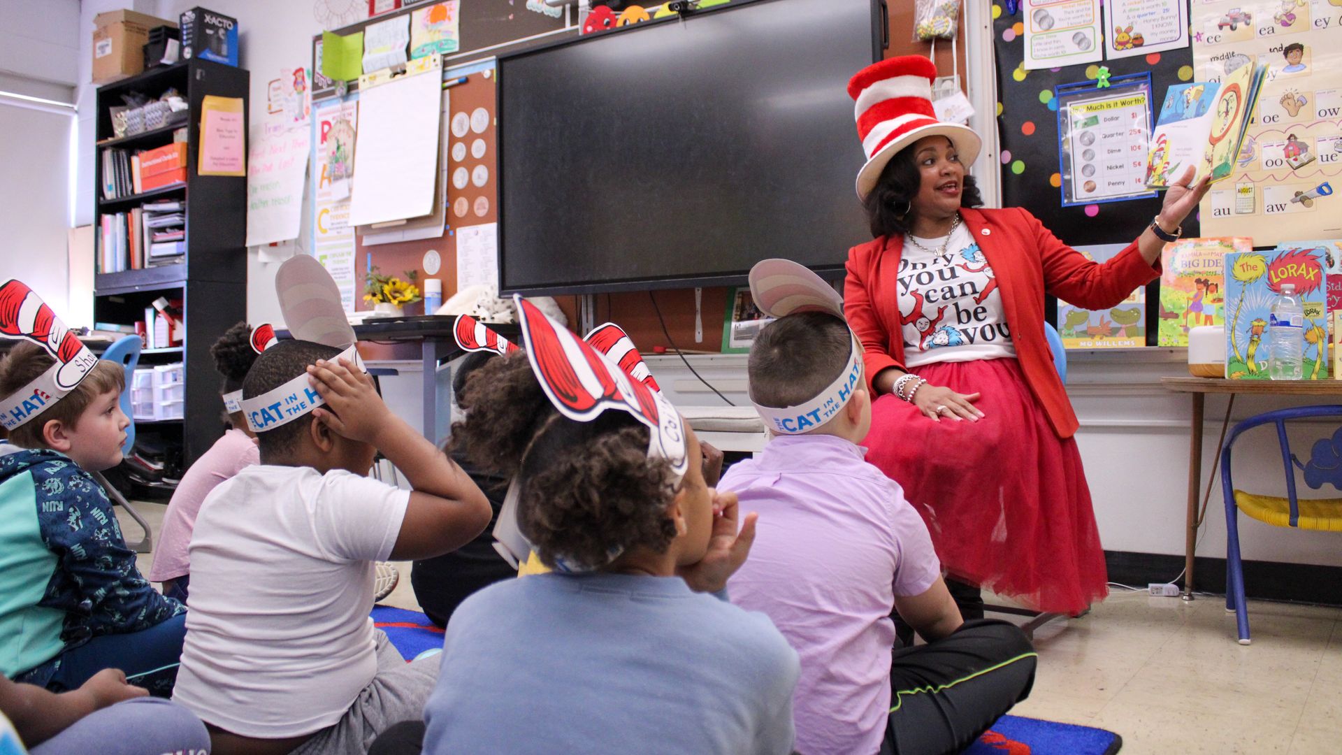 Columbus City Schools superintendent Angela Chapman reads to a group of seated children while wearing a "Cat in the Hat" hat