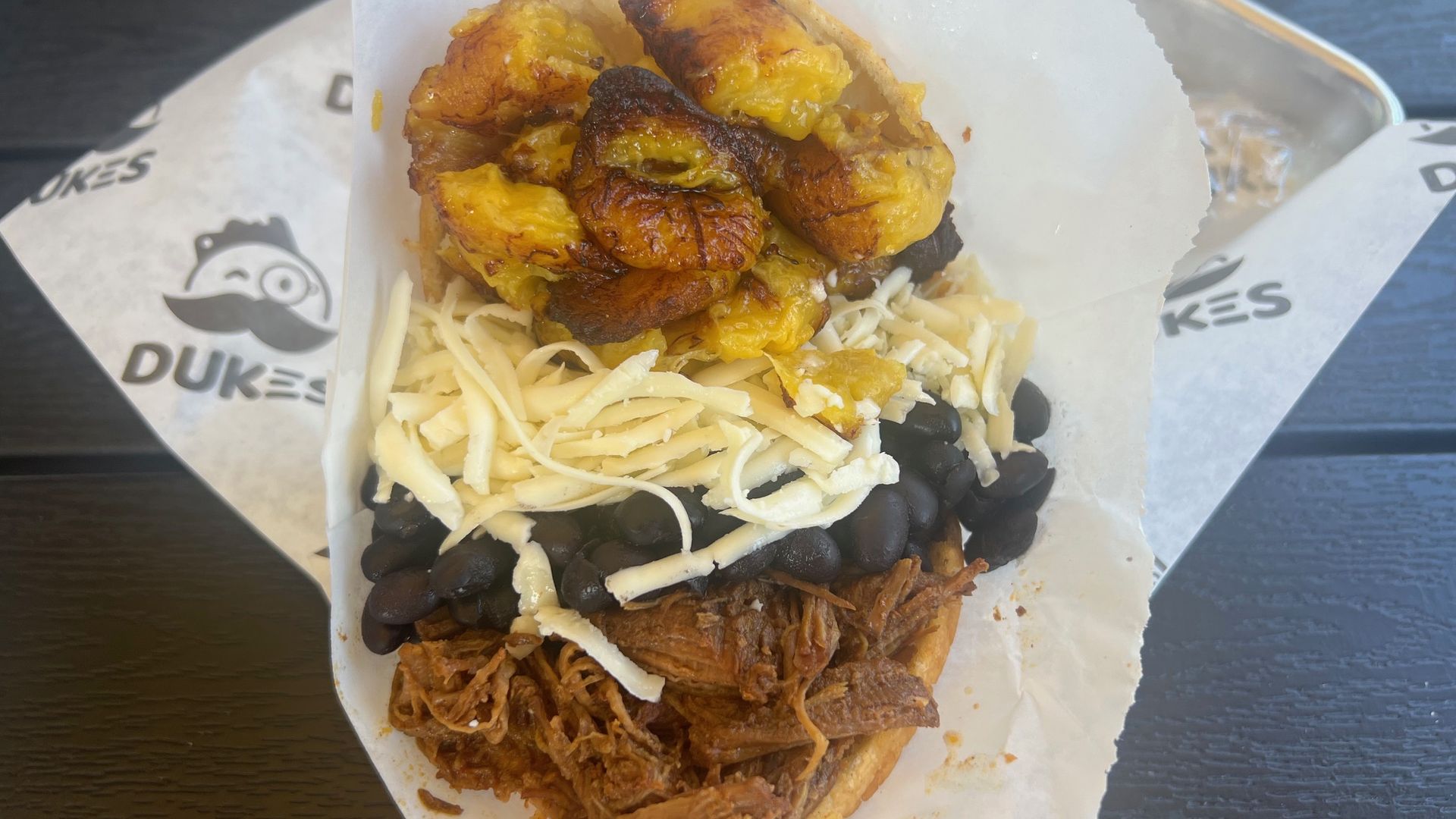 An arepa filled with plantains, queso fresco, black beans and shredded beef.