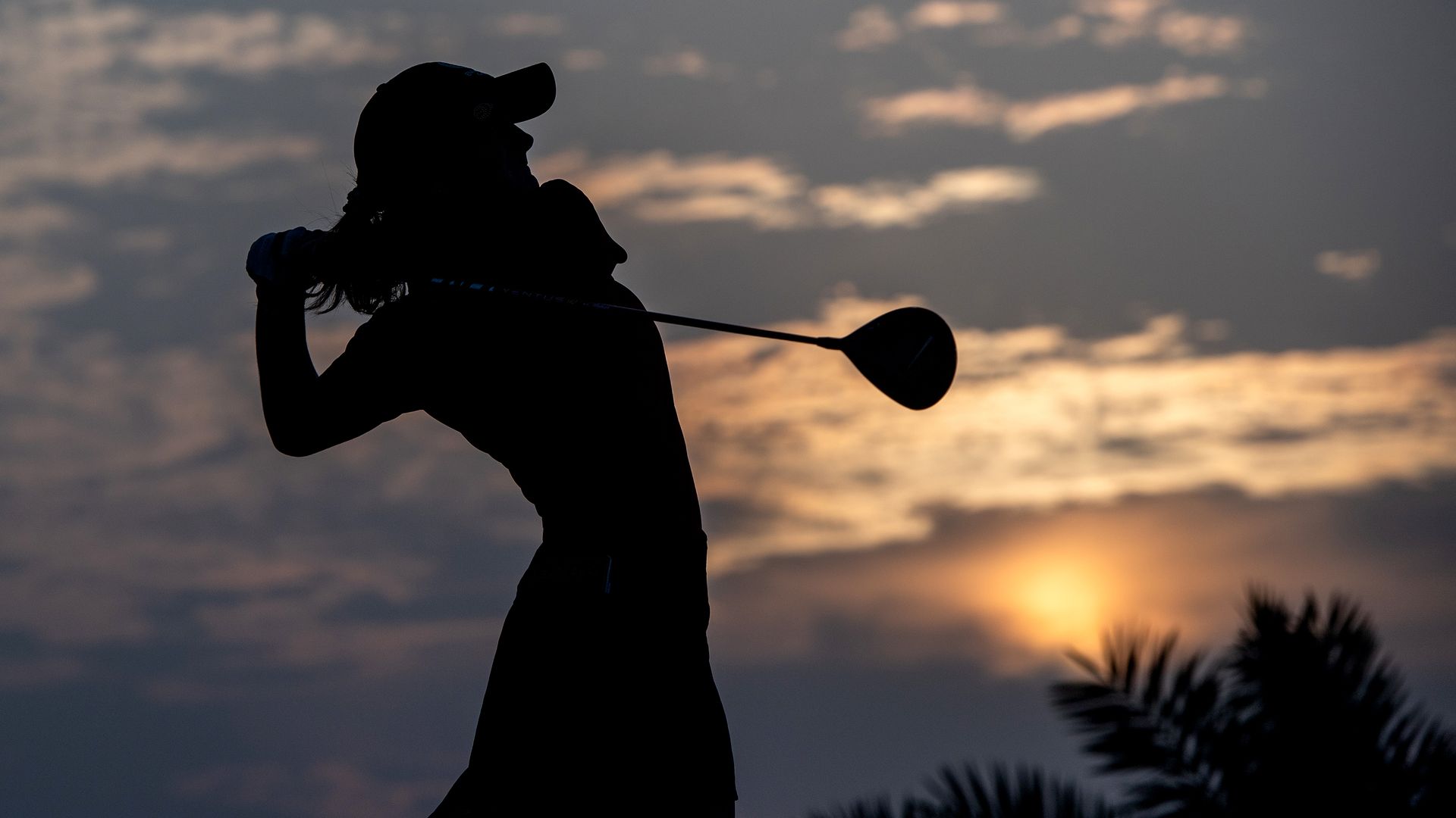 A golfer playing at sunset