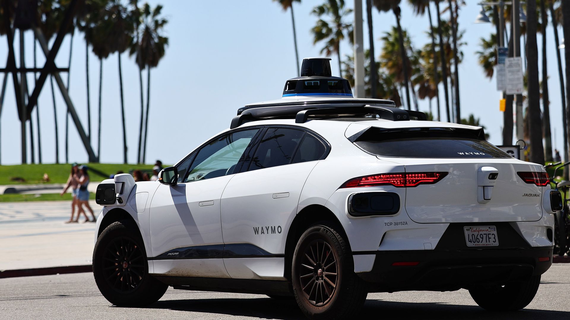 A white crossover equipped with self-driving car systems drives near the ocean