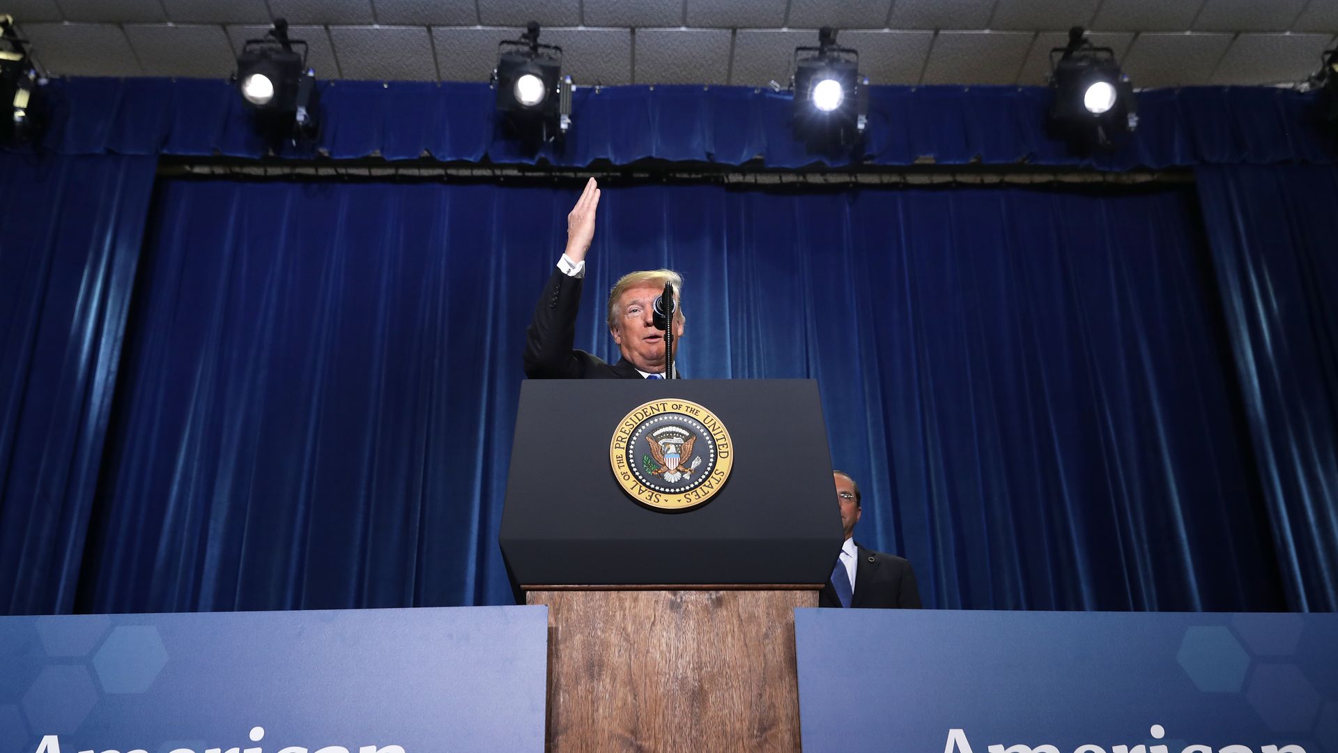 In this image, President Trump speaks behind a podium with the presidential seal on it.