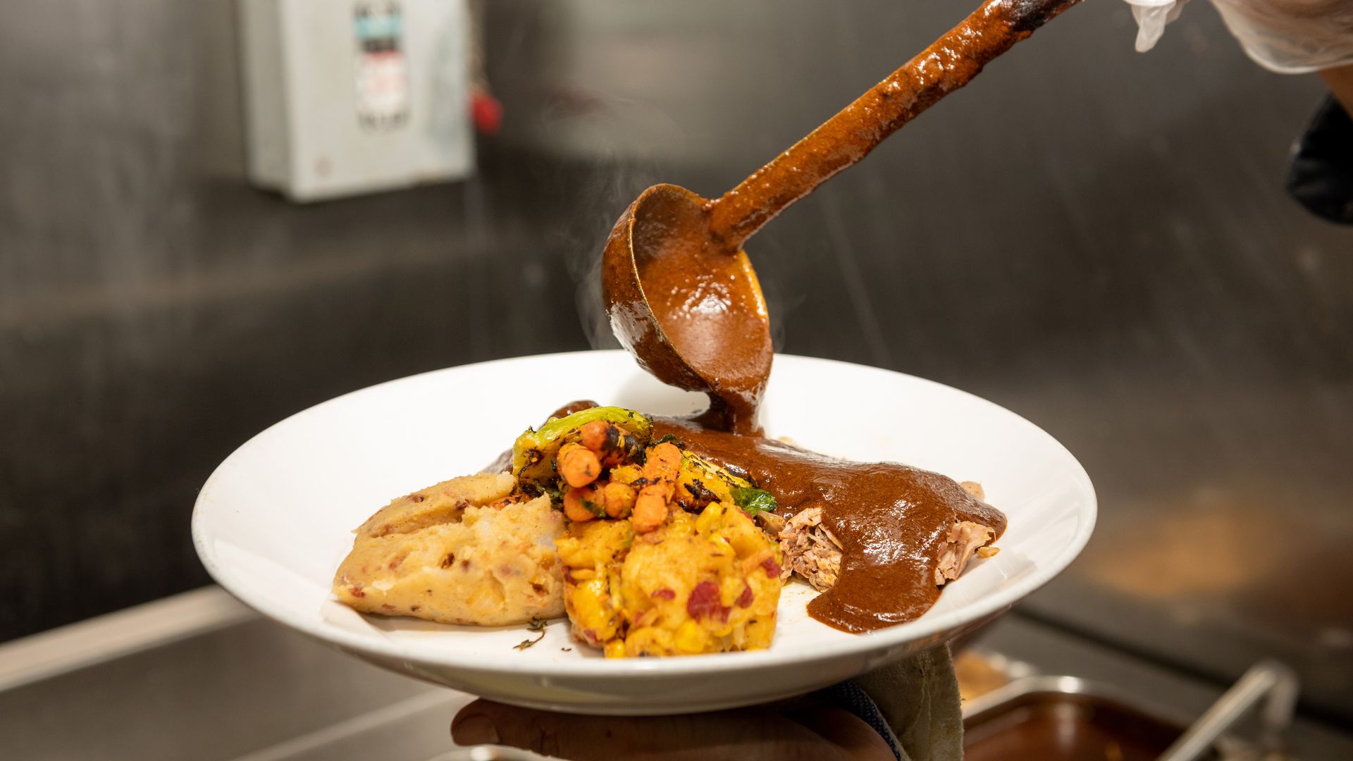 Mole sauce being ladled over a Thanksgiving turkey dinner at Rosa Mexicano restaurant in New York City