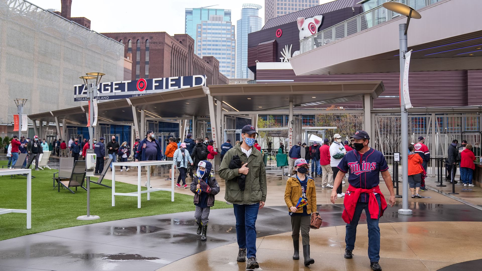 Fans walk into Target Field for a baseball games, wearing masks 
